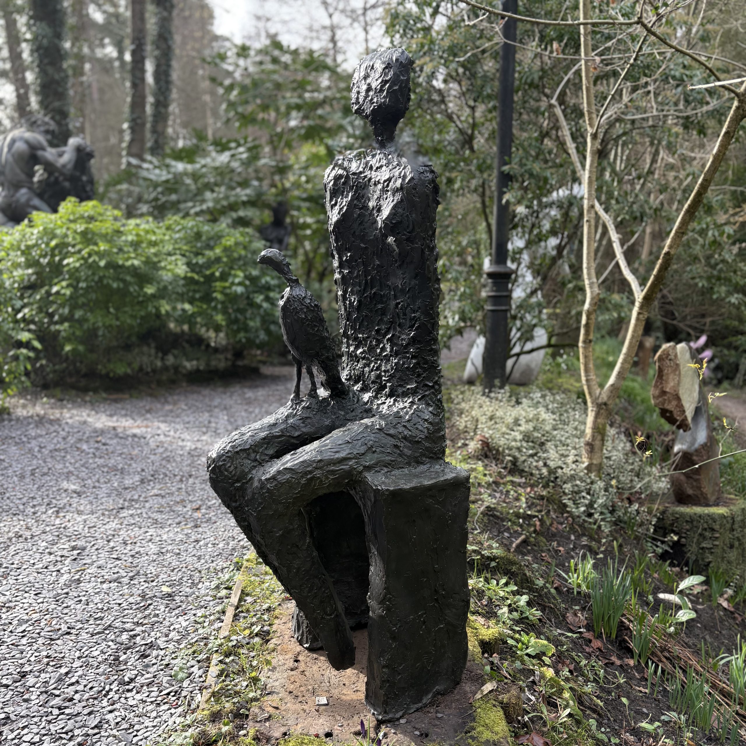 Companion by Wendy Fisher is a simple figurative bronze sculpture of a seated woman with a kestrel bird on her lap