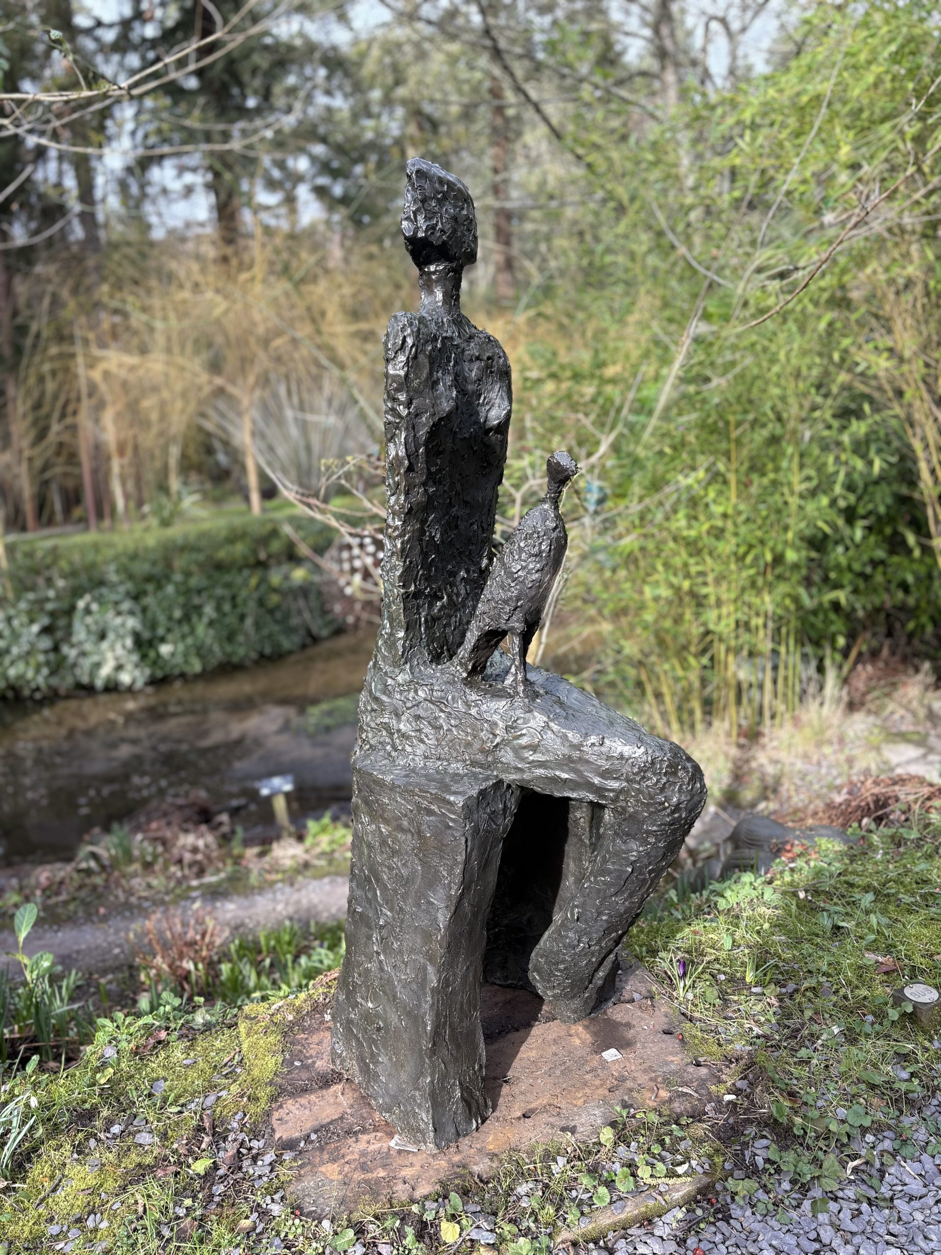 Companion by Wendy Fisher is a simple figurative bronze sculpture of a seated woman with a kestrel bird on her lap.