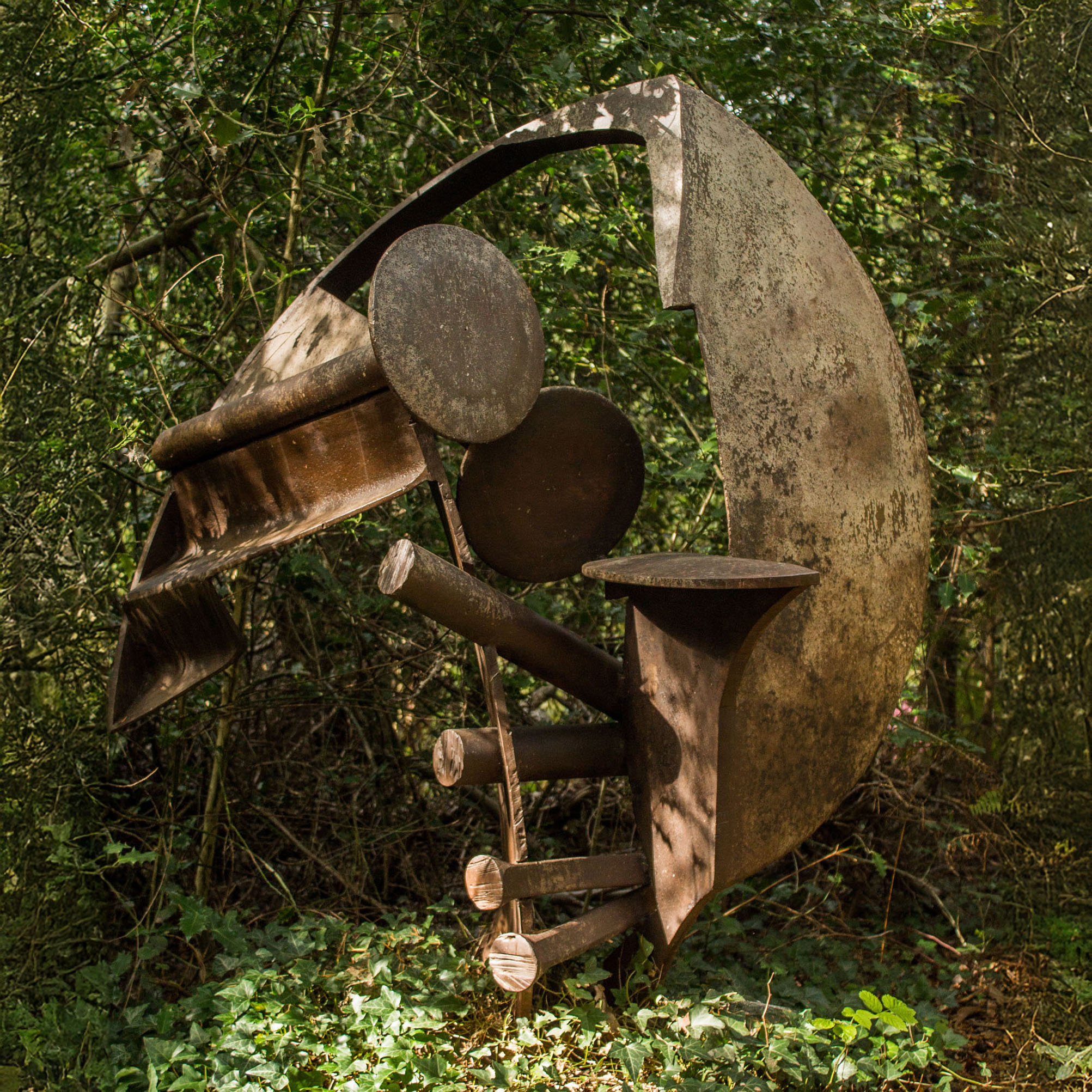 A abstract steel sculpture of various pieces of metal welded into a curved yet jagged shape.