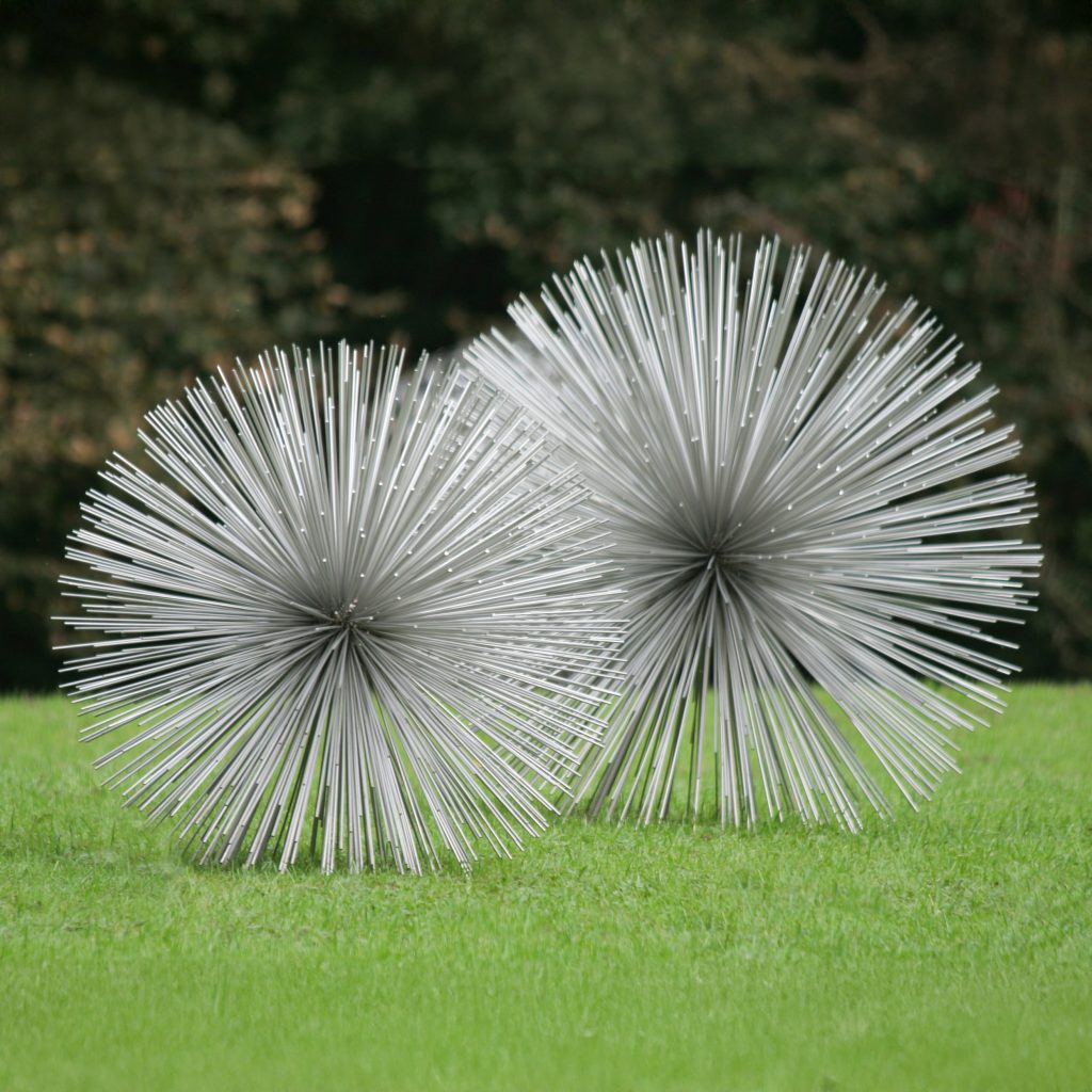 A floral stainless steel sculpture of two different sized spiky seedheads.