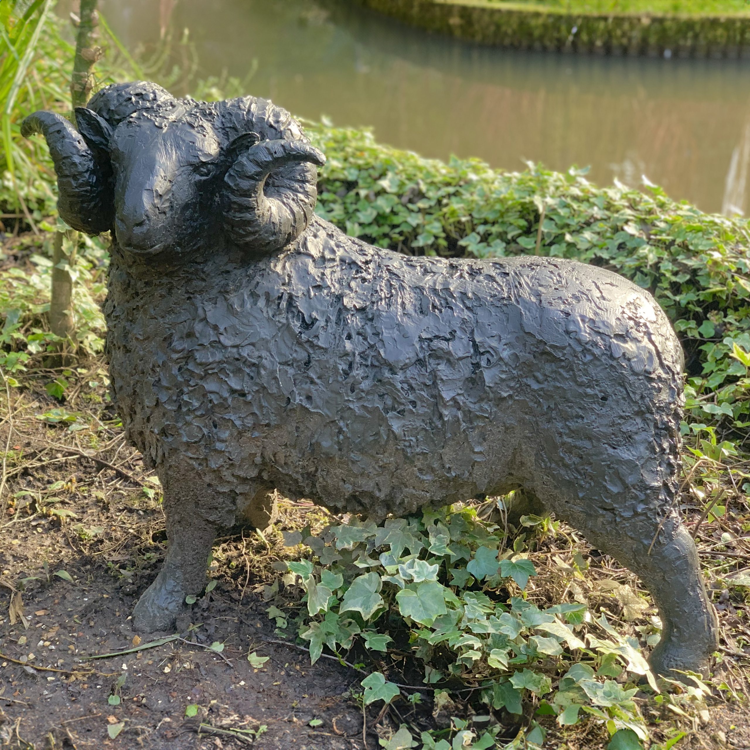 A figurative bronze sculpture of a ram with a wide stance.