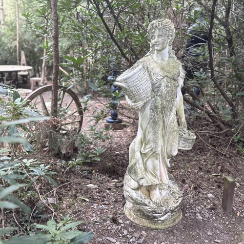 Lady Carrying Baskets by After The Antique is a cast stone, weather-aged sculpture of a girl going to market suitable for outdoor display