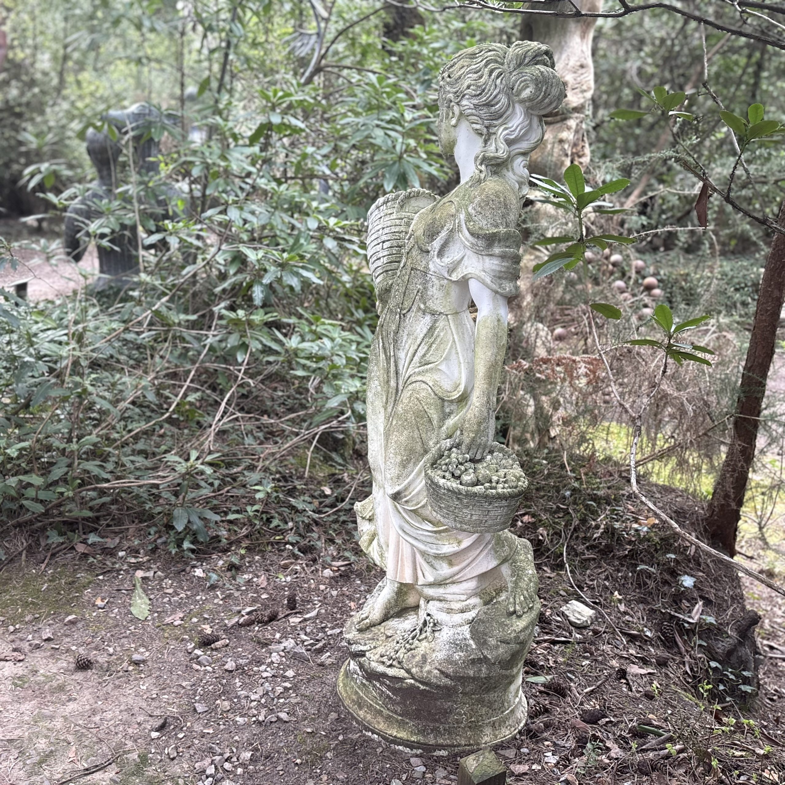 Lady Carrying Baskets by After The Antique is a cast stone, weather-aged sculpture of a girl going to market suitable for outdoor display