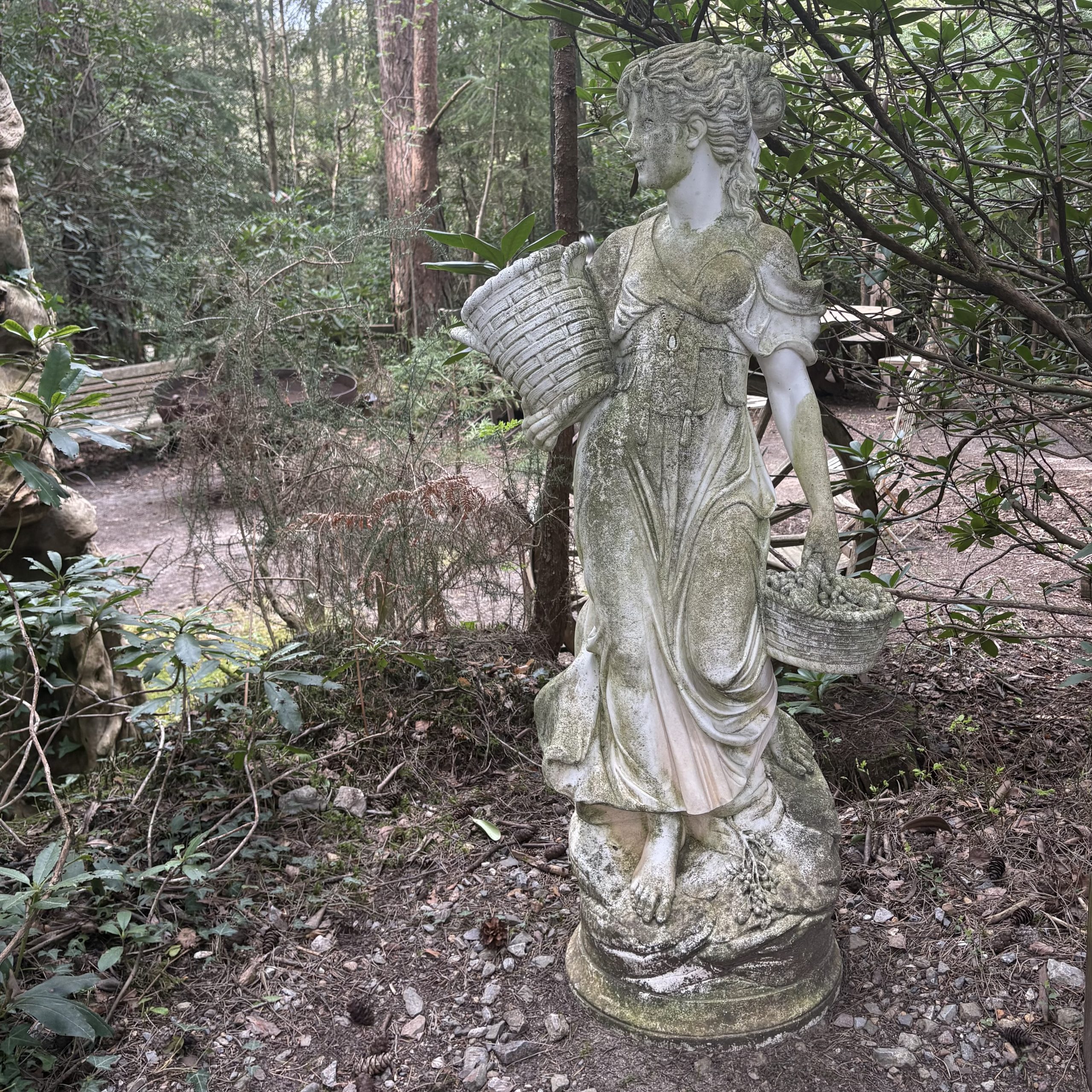 Lady Carrying Baskets by After The Antique is a cast stone, weather-aged sculpture of a girl going to market suitable for outdoor display
