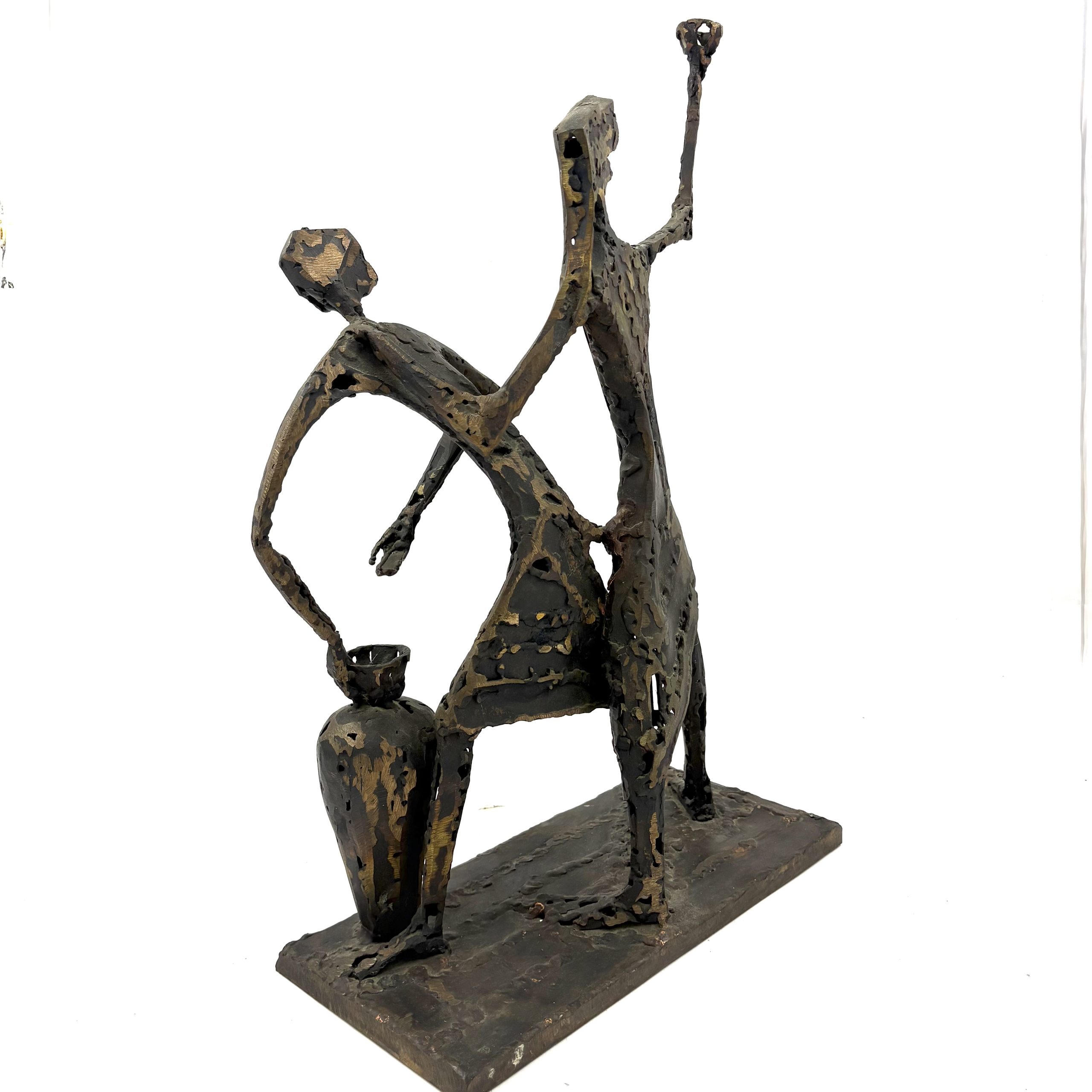 Two Figures by Sean Crampton. A unique sculpture made from welded bronze depicting two figures standing side by side along with a large vessel or vase.
