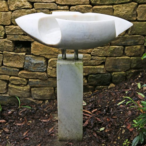 Channel Stone by Joan Roberts. Large abstract white marble sculpture. The elongated shell like shape is held with steel posts on a marble plinth.