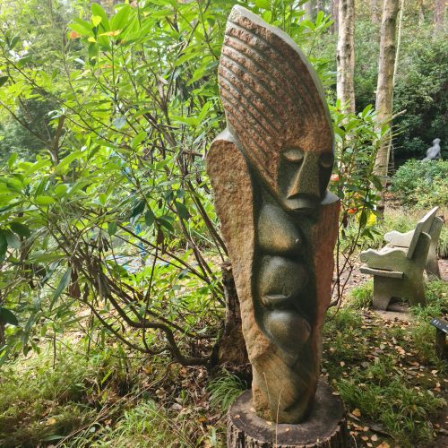 A unique, large sculpture made from Serpentine stone. The abstract style piece depicts a mother protecting her child.