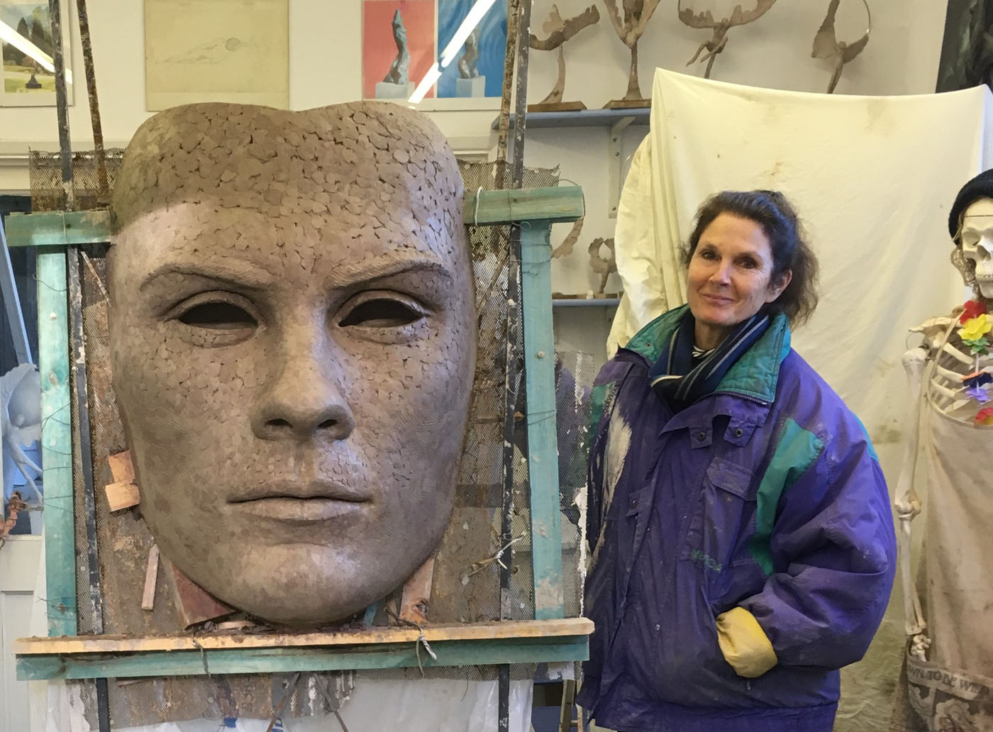 Mask of Achilles by Nicola Godden. A large bronze resin mask sculpture of the face of the Greek warrior, Achilles. Displayed on top of a wooden plinth.
