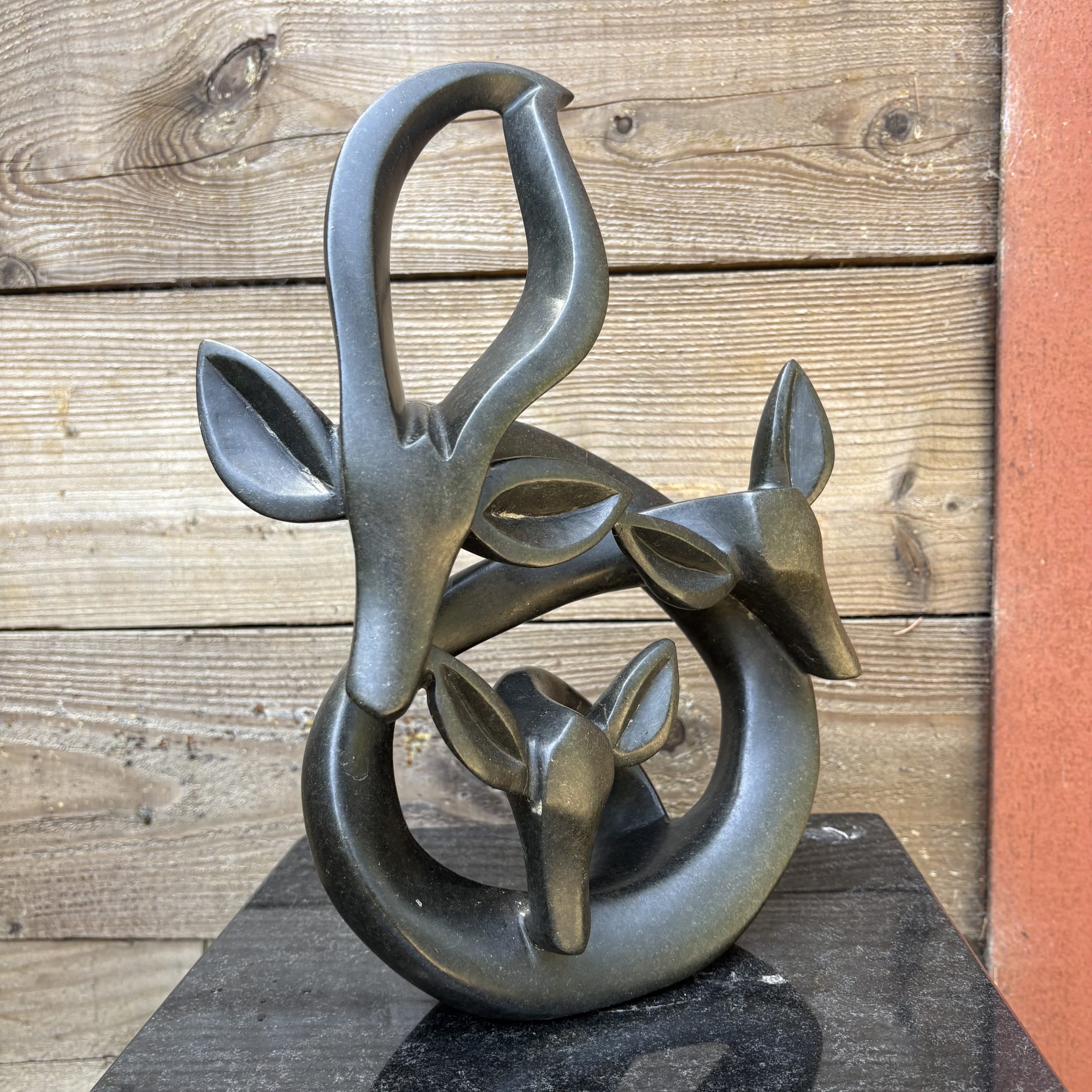 Celebration Family by Fungai Dodzo, Table-top sized Shona Springstone sculpture of an abstract depiction of family of three Impala.
