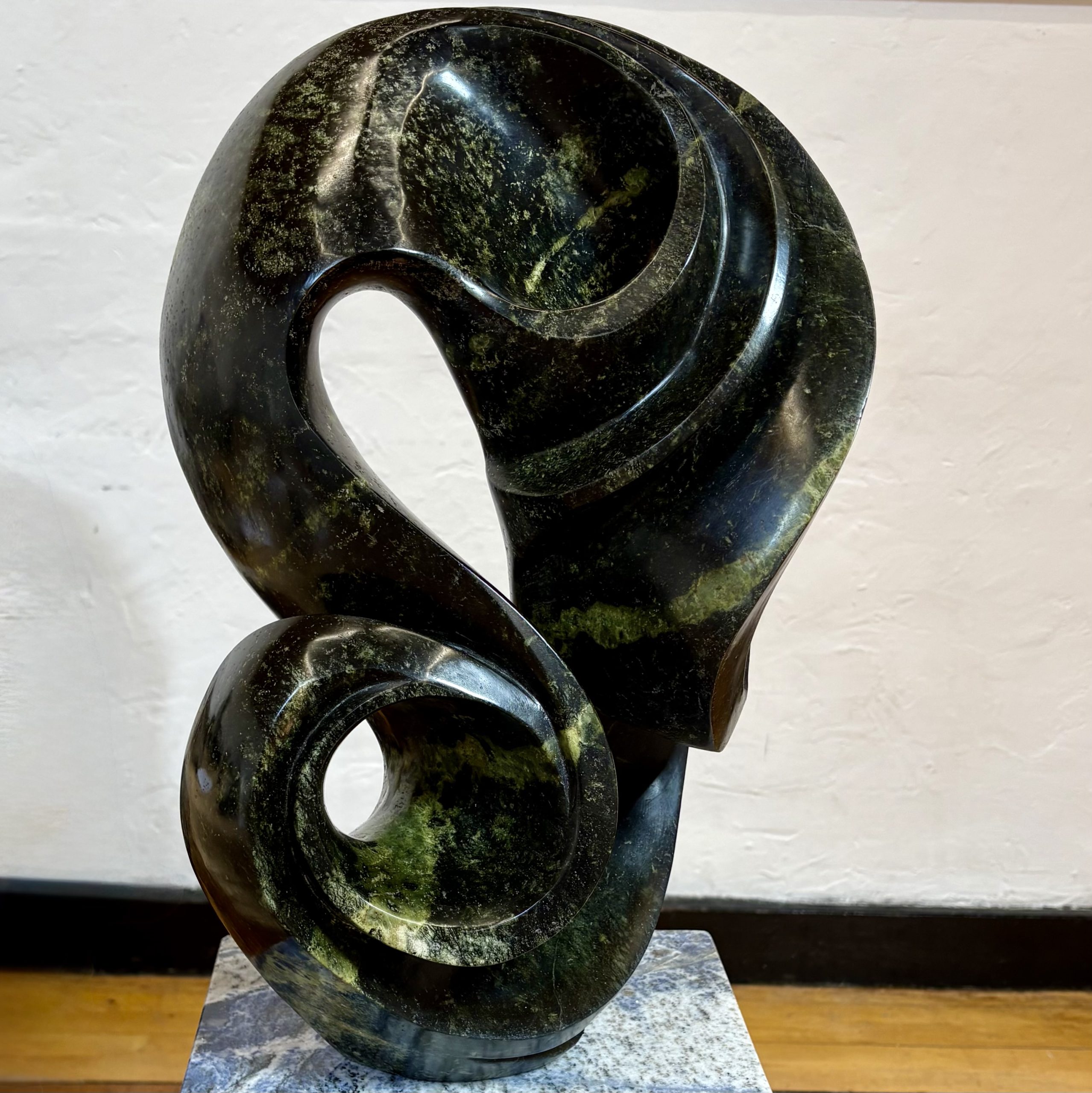 Life on Earth by Kufa McDonald. Unique sculpture made from avocado stone with green hues. The piece swirls and curves in an abstract yet naturalistic style.