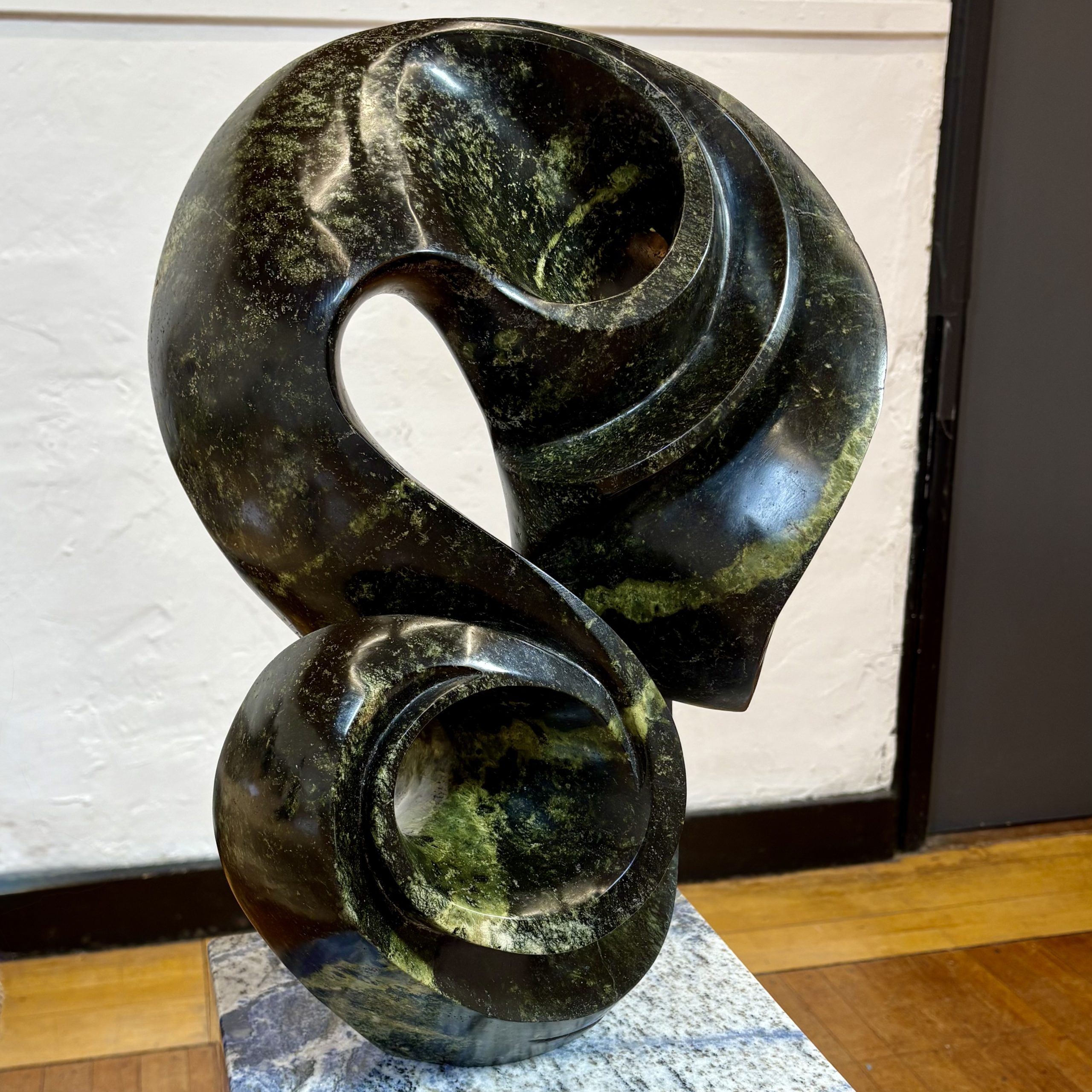 Life on Earth by Kufa McDonald. Unique sculpture made from avocado stone with green hues. The piece swirls and curves in an abstract yet naturalistic style.