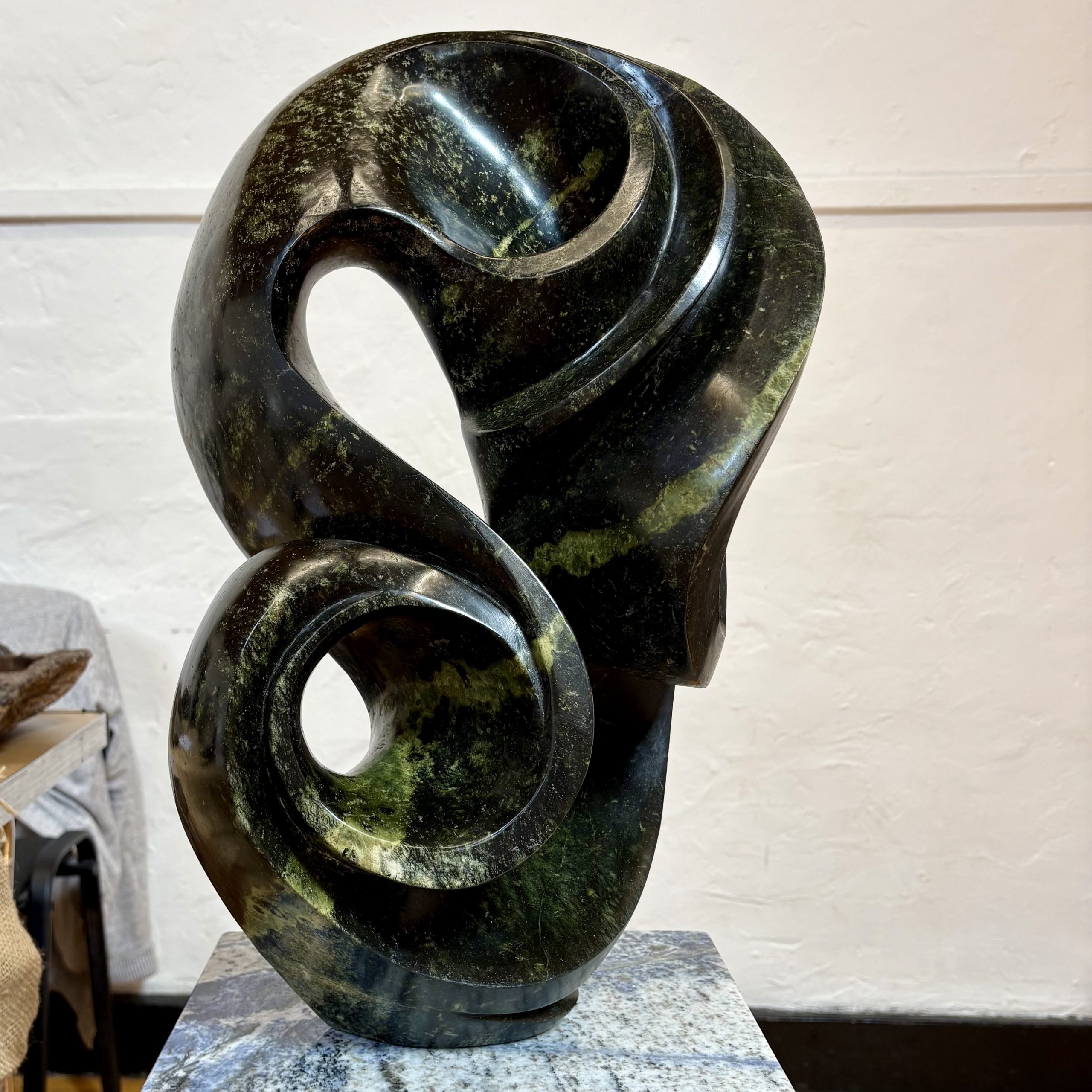 Life on Earth by Kufa McDonald. Unique sculpture made from avocado stone with green hues. The piece swirls and curves in an abstract yet naturalistic style.