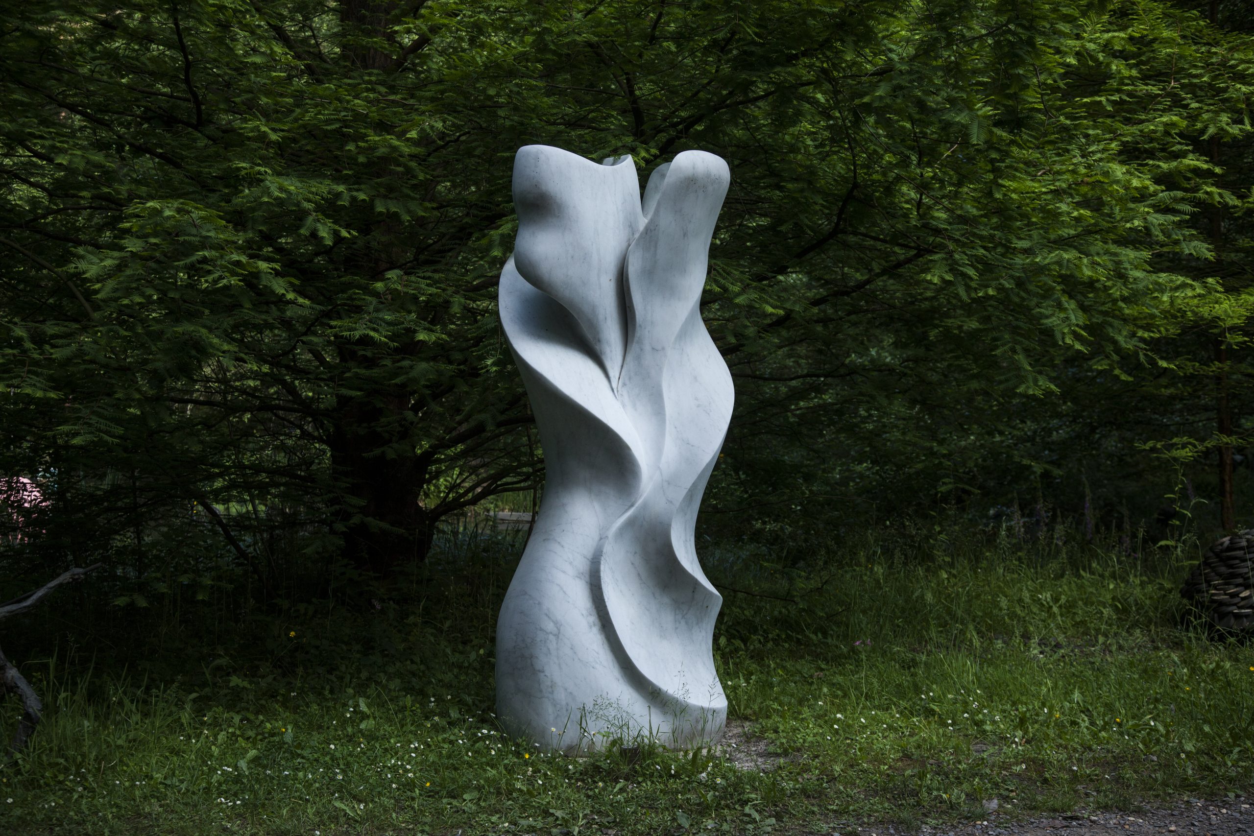 Enlaced by Frederic Chevaric. Large white abstract marble sculpture with wave-like carved formations.