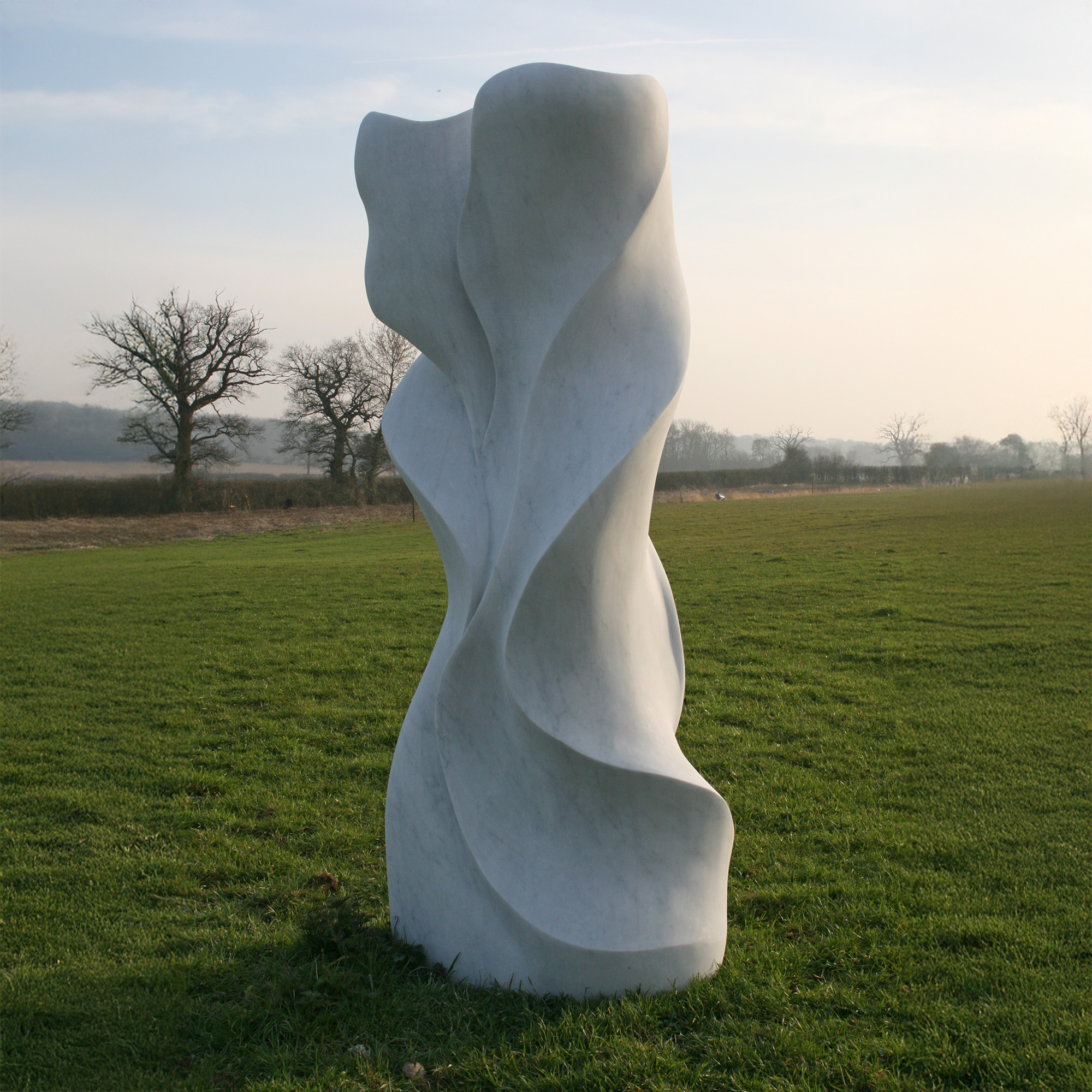 Enlaced by Frederic Chevaric is a striking large abstract sculpture carved from beautiful white Carrara marble into sweeping, wave-like carved formations.