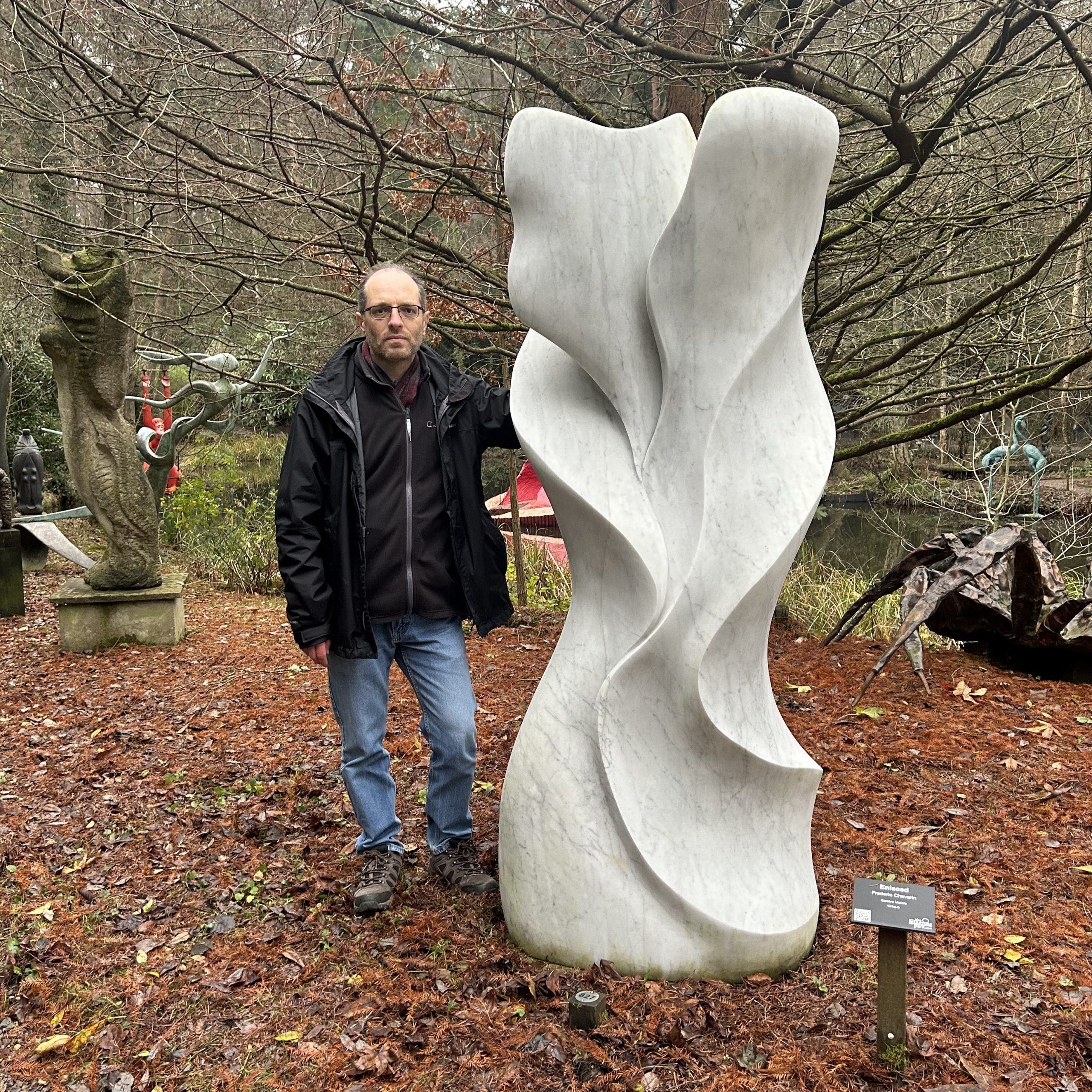 Enlaced by Frederic Chevaric. Large white abstract marble sculpture with wave-like carved formations.