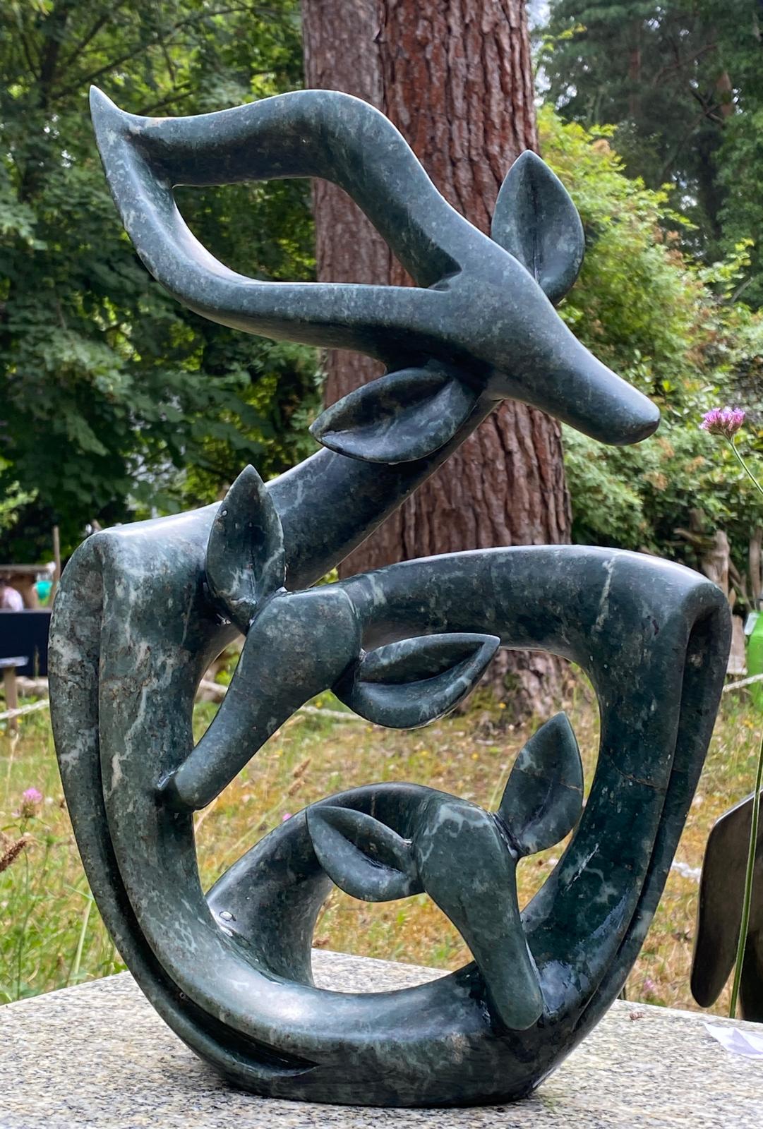 Celebrating our New Born by Fungai Dodzo, a Shona stone sculpture of a family of 3 gazelles with their forms all connected as one.