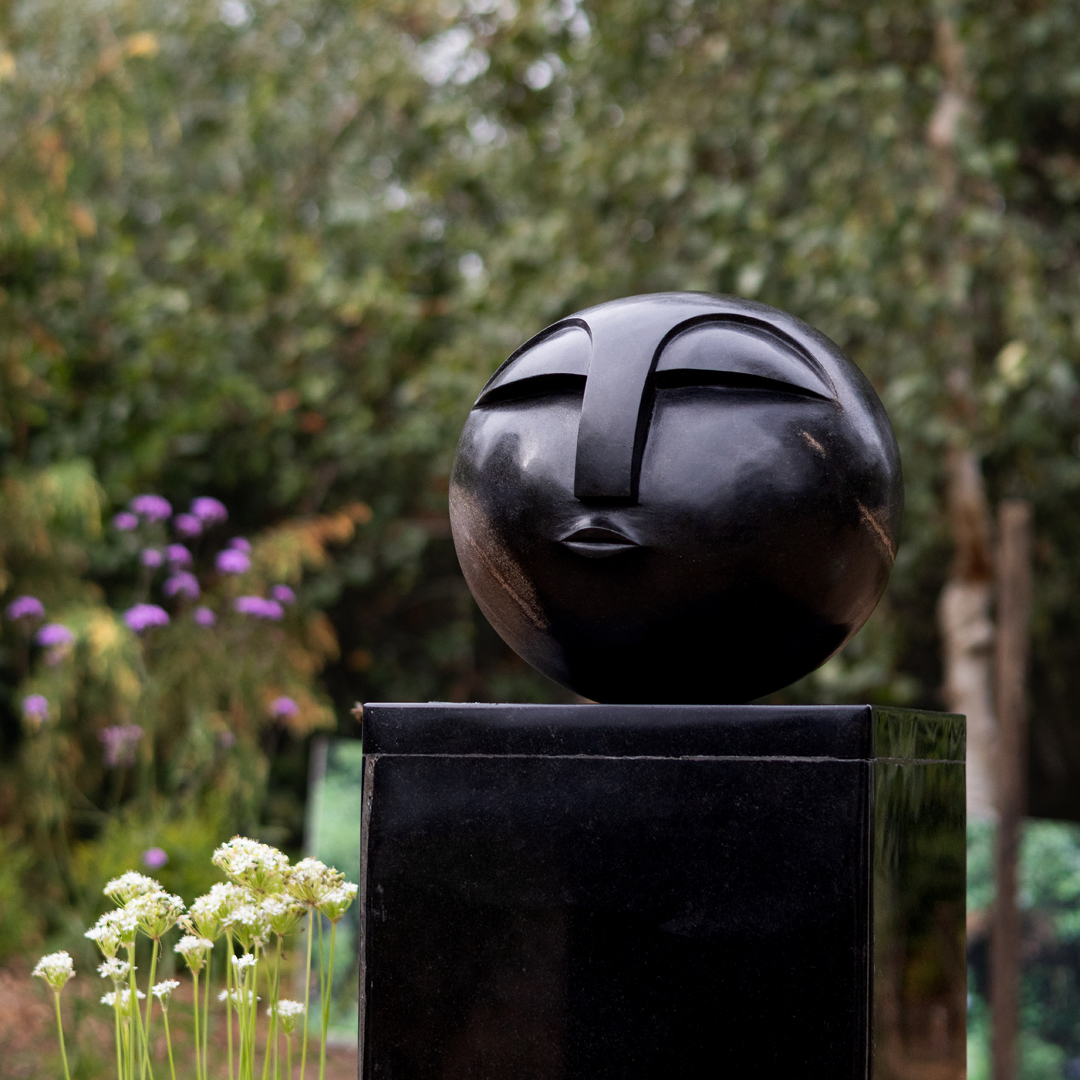 Sun Face by Addington Nyamasoka, a Shona Springstone sculpture of a rounded head with a face.