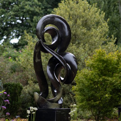 Cherished by James Phiri, a Shona Avocado stone sculpture of a tall abstract shape that curls and twists as it rises.