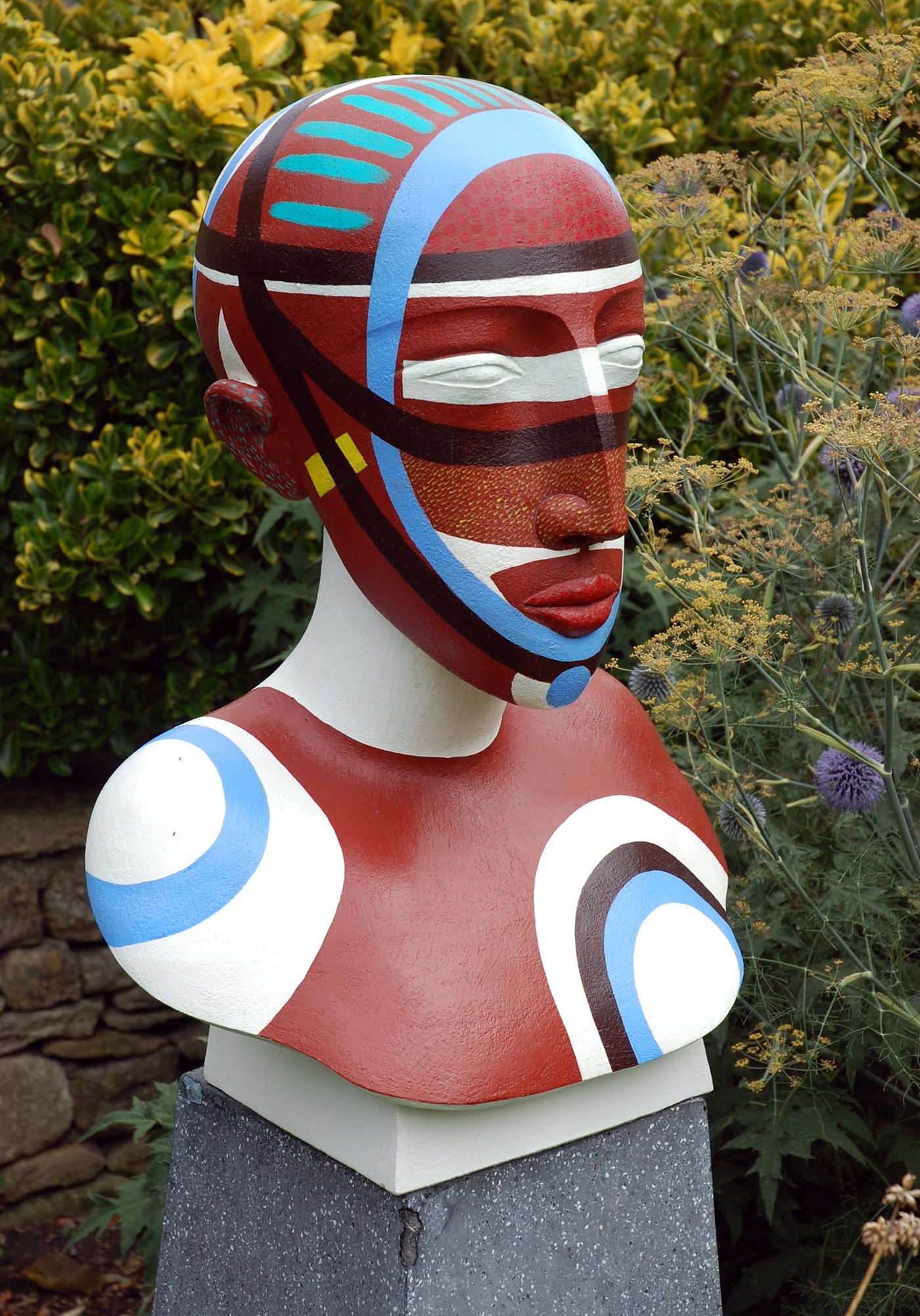 A figurative stoneware sculpture of a portrait bust of a person painted with various colours.