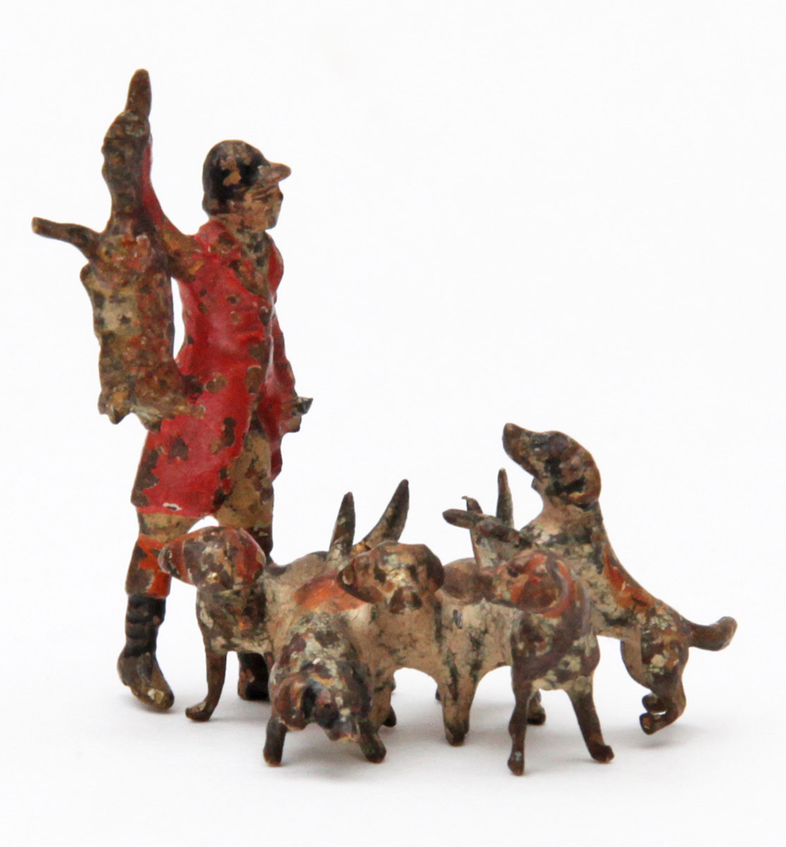A figurative painted bronze sculpture of a hunter holding up a fox in front of a group of dogs.