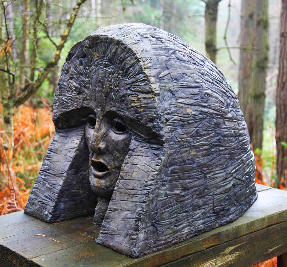 A classical bronze resin sculpture of a persons head with a large head piece.