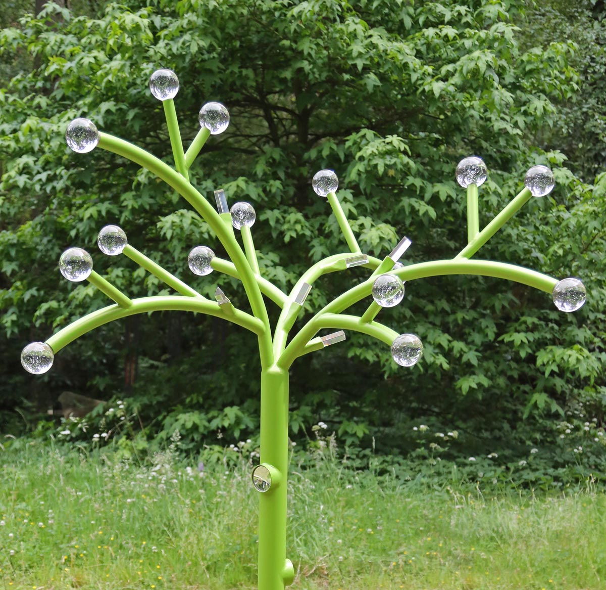 A floral metal sculpture of a tree shape with glass balls at the end of each branch.