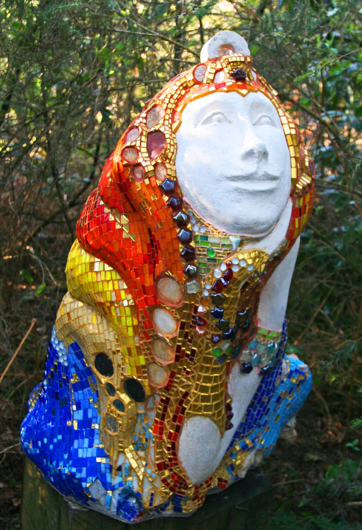A figurative ceramic and glass sculpture of a lady covered in a colourful mosaic.