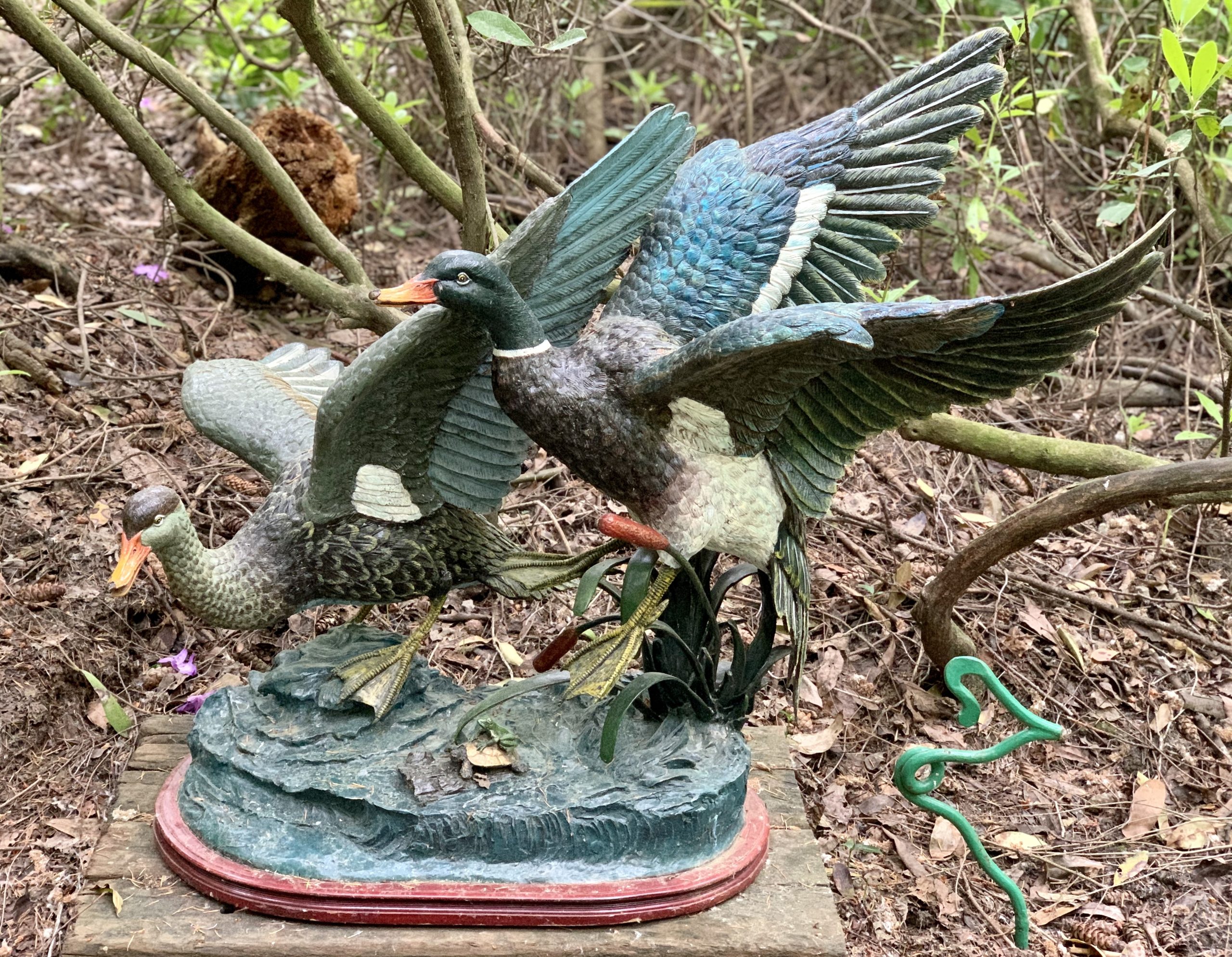 A figurative bronze sculpture of a pair of ducks taking flight.