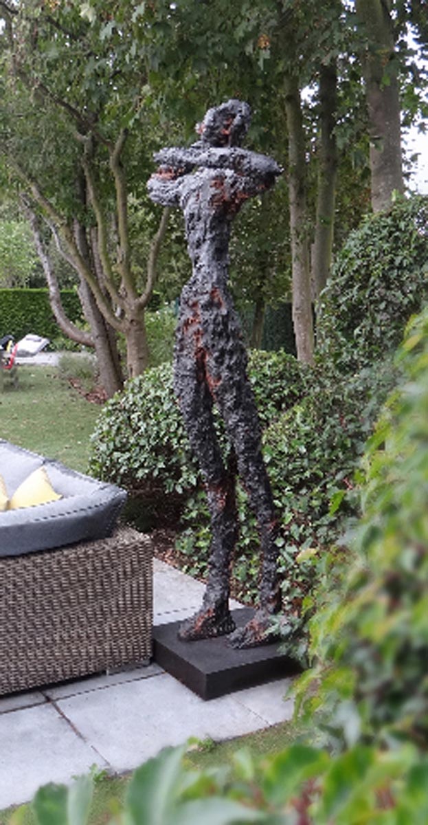 A figurative bronze sculpture of a person standing and stretching.