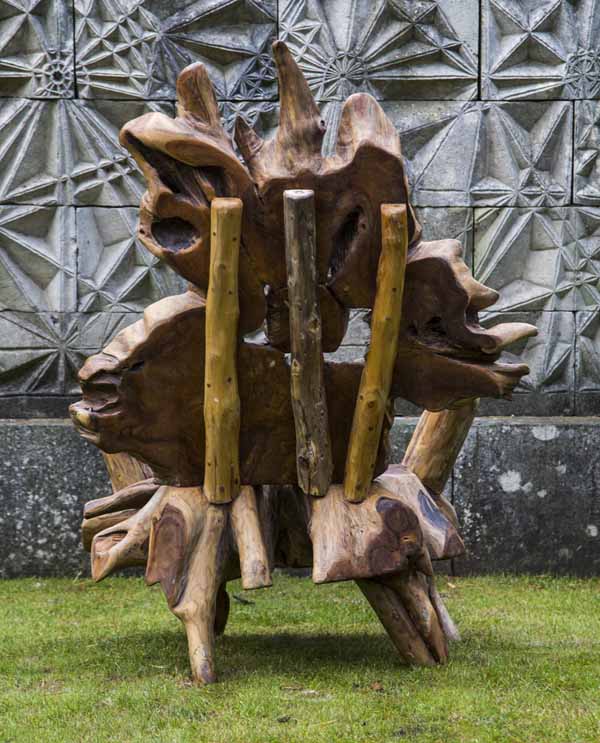 A furniture teak wood sculpture of a arm chair made from a tree root.