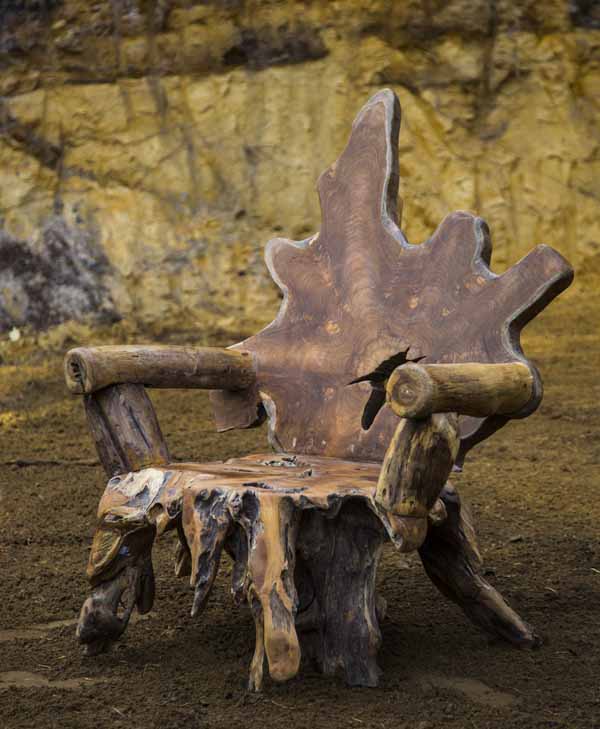 A furniture teak wood sculpture of a arm chair made from a tree root.