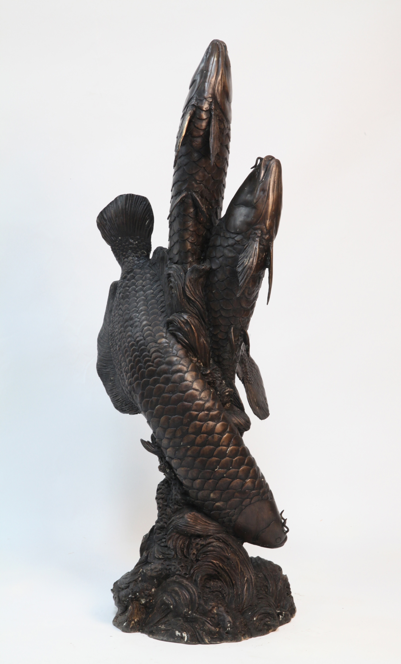 A classical and realistic bronze sculpture of three carp.