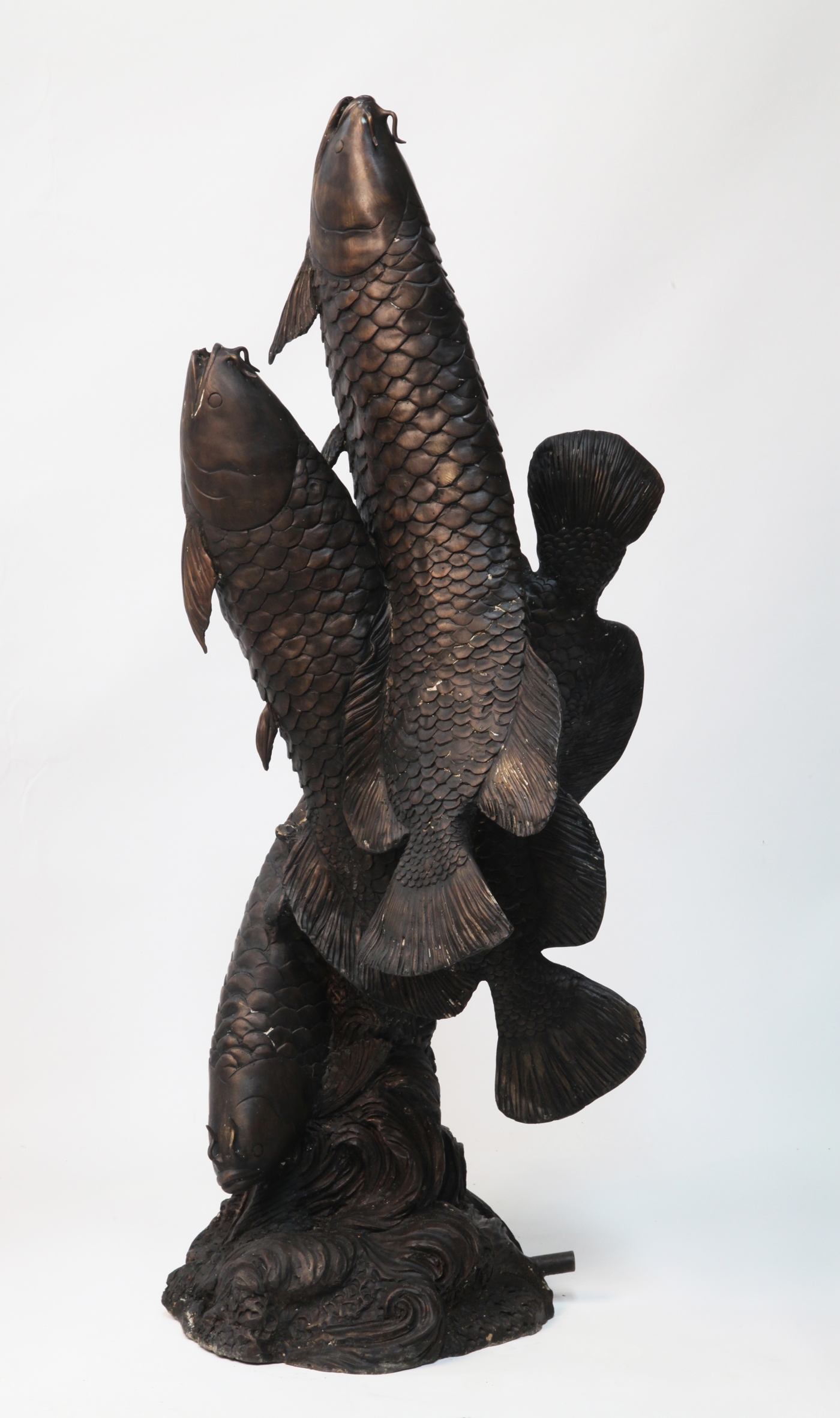 A classical and realistic bronze sculpture of three carp.