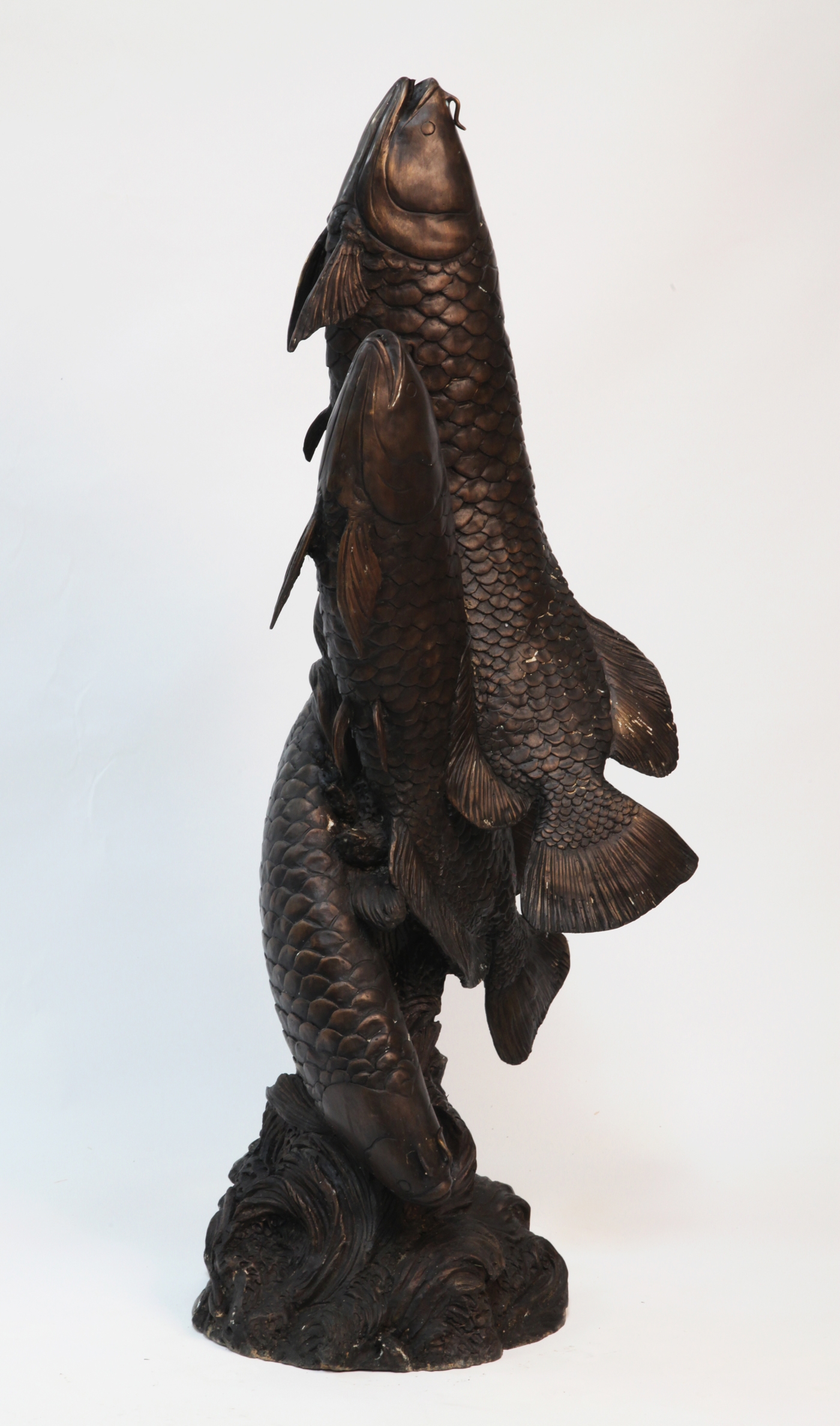 A classical and realistic bronze sculpture of three carp.