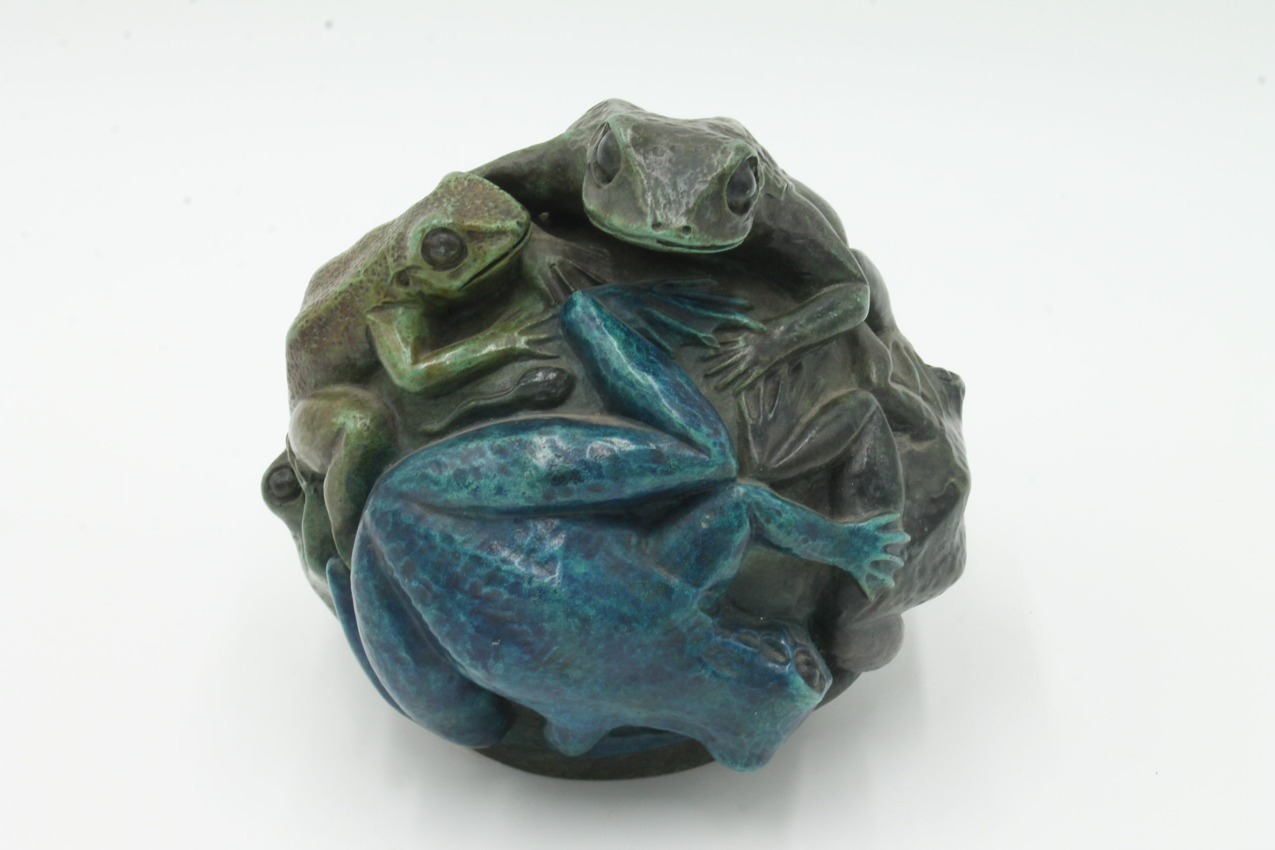 A contemporary bronze sculpture of a group of frogs all formed together into a ball.