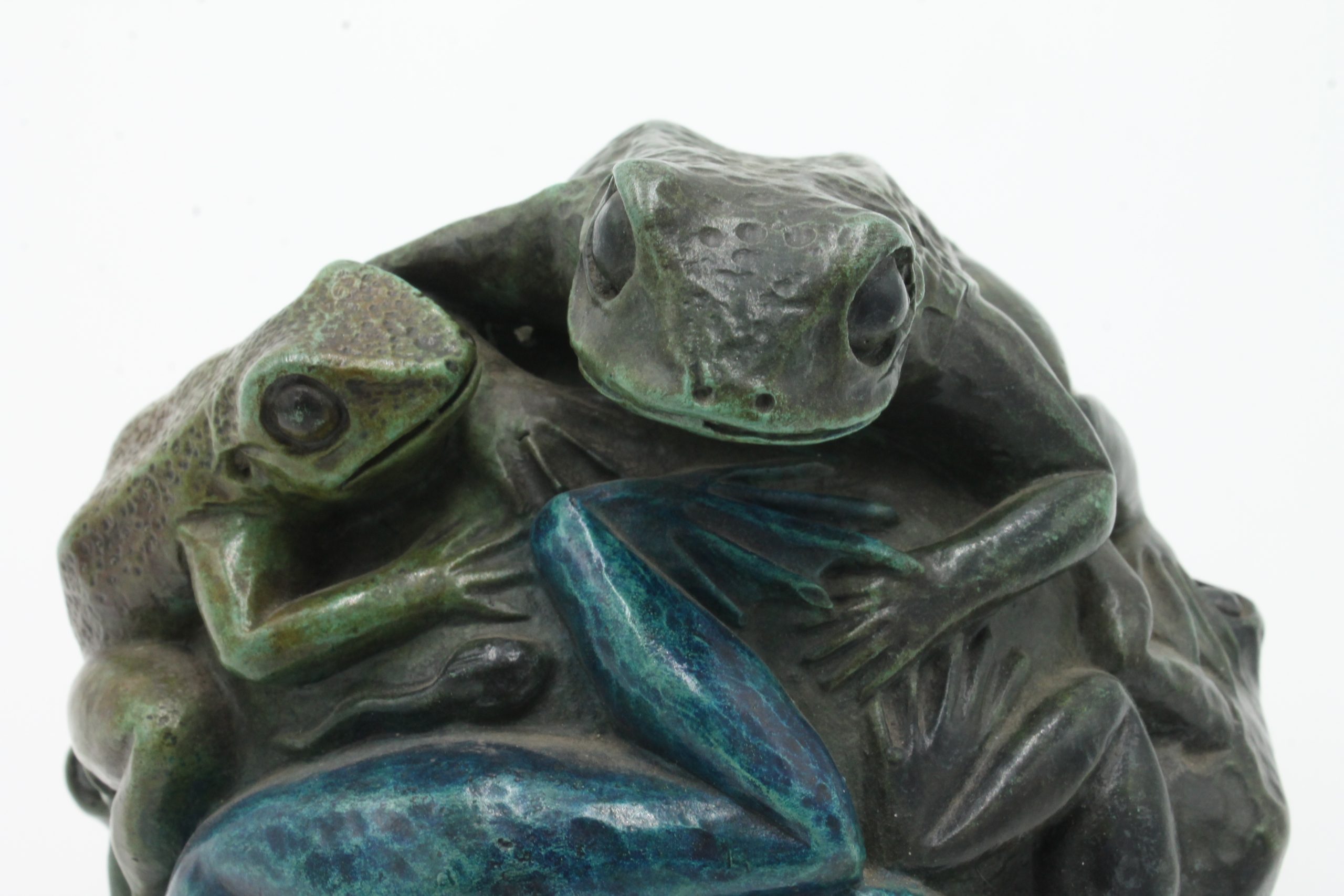 A contemporary bronze sculpture of a group of frogs all formed together into a ball.