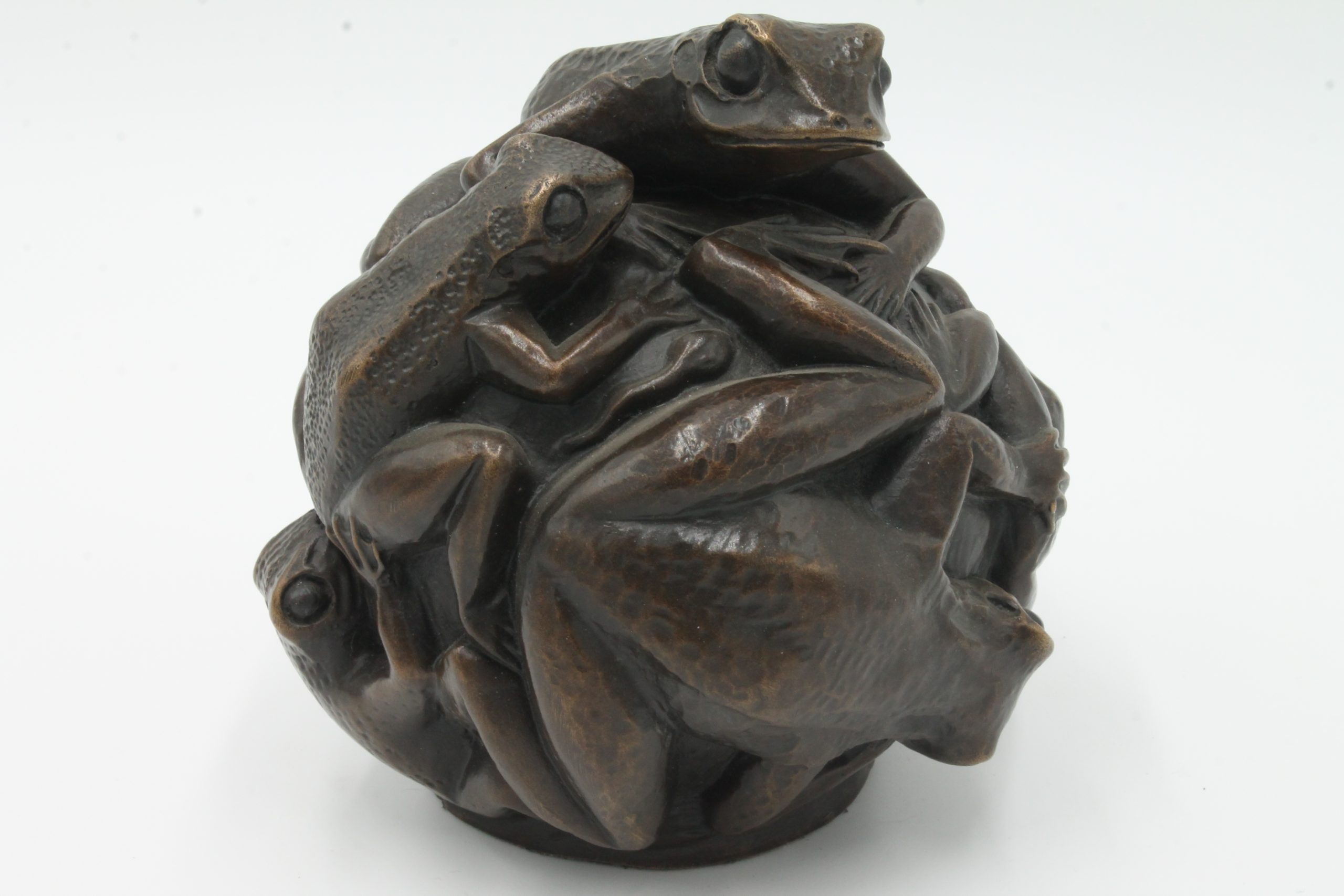 A contemporary bronze sculpture of a group of frogs all formed together into a ball.