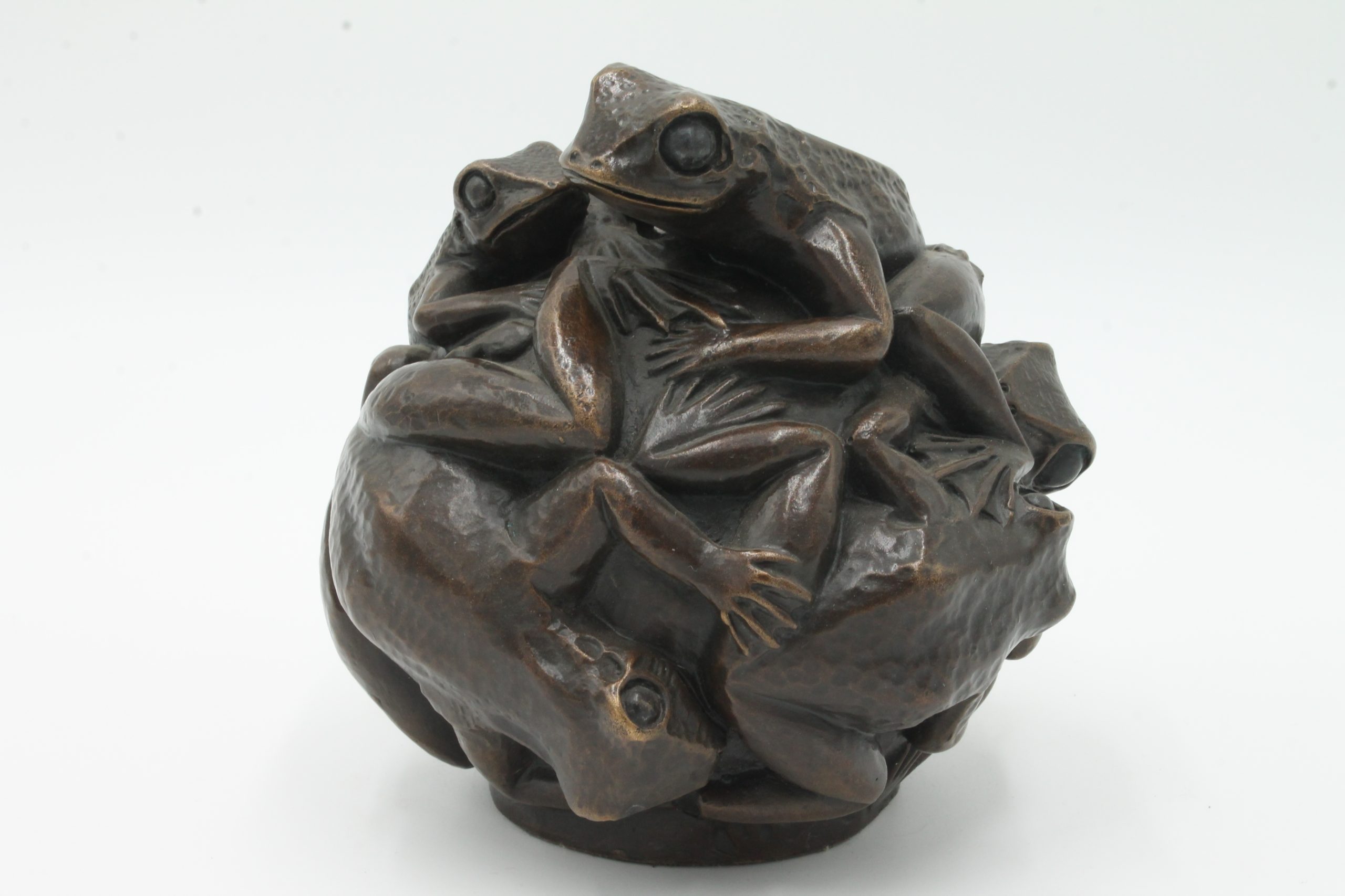 A contemporary bronze sculpture of a group of frogs all formed together into a ball.