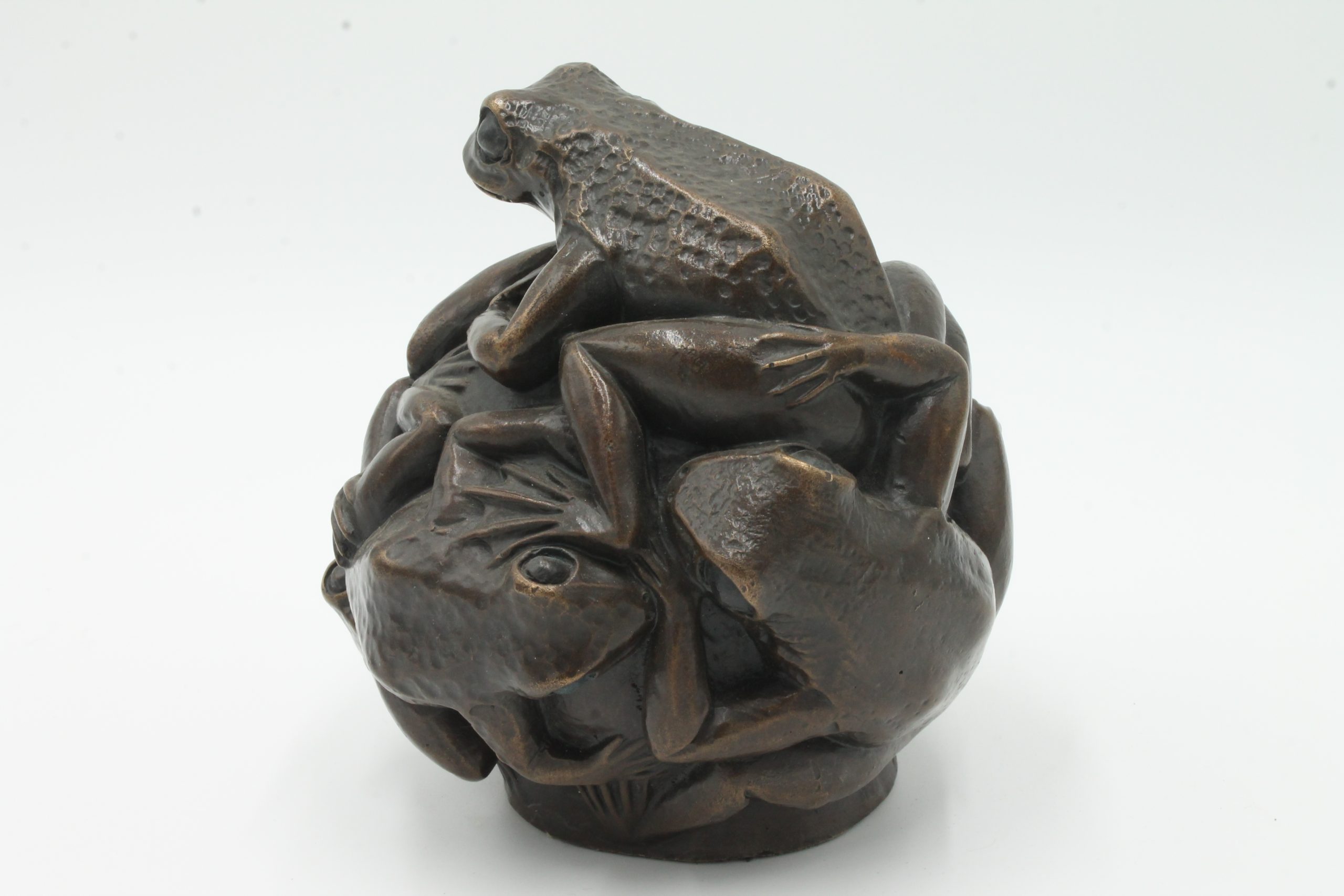 A contemporary bronze sculpture of a group of frogs all formed together into a ball.