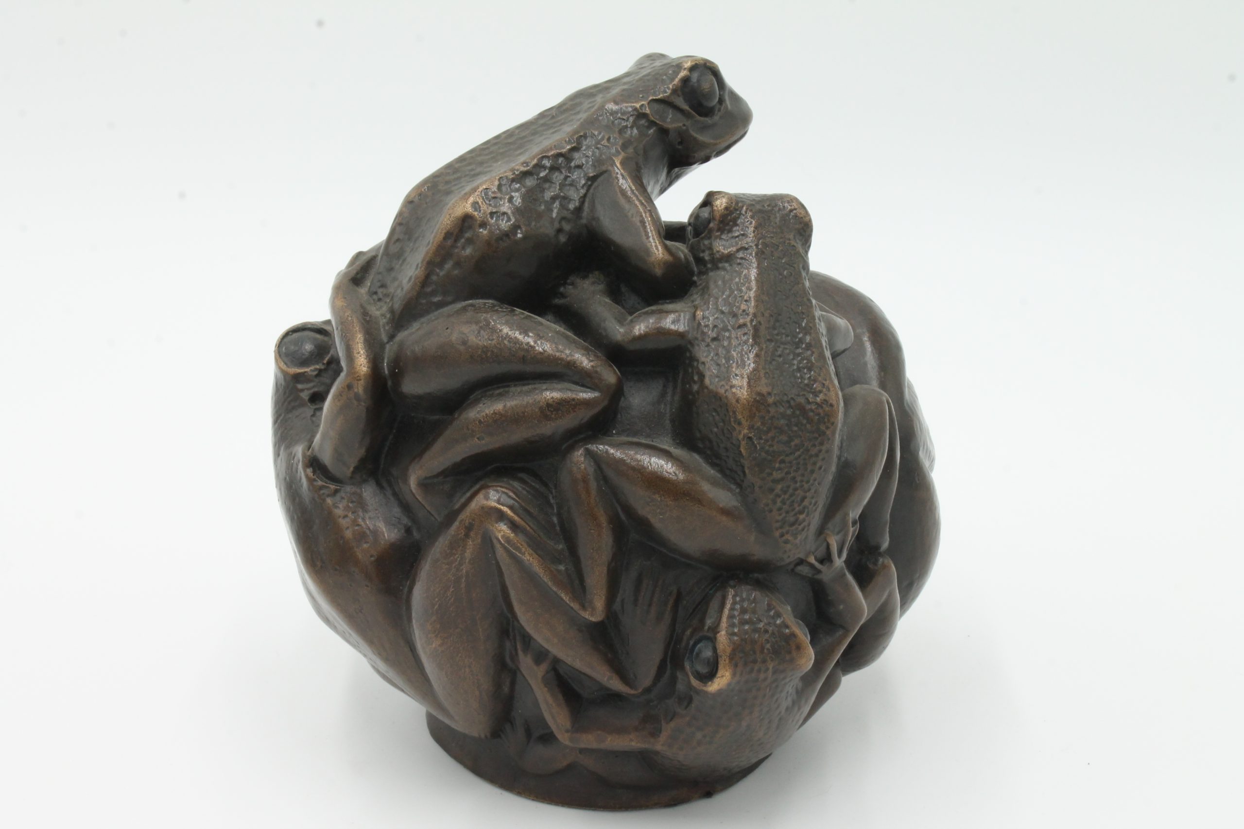 A contemporary bronze sculpture of a group of frogs all formed together into a ball.