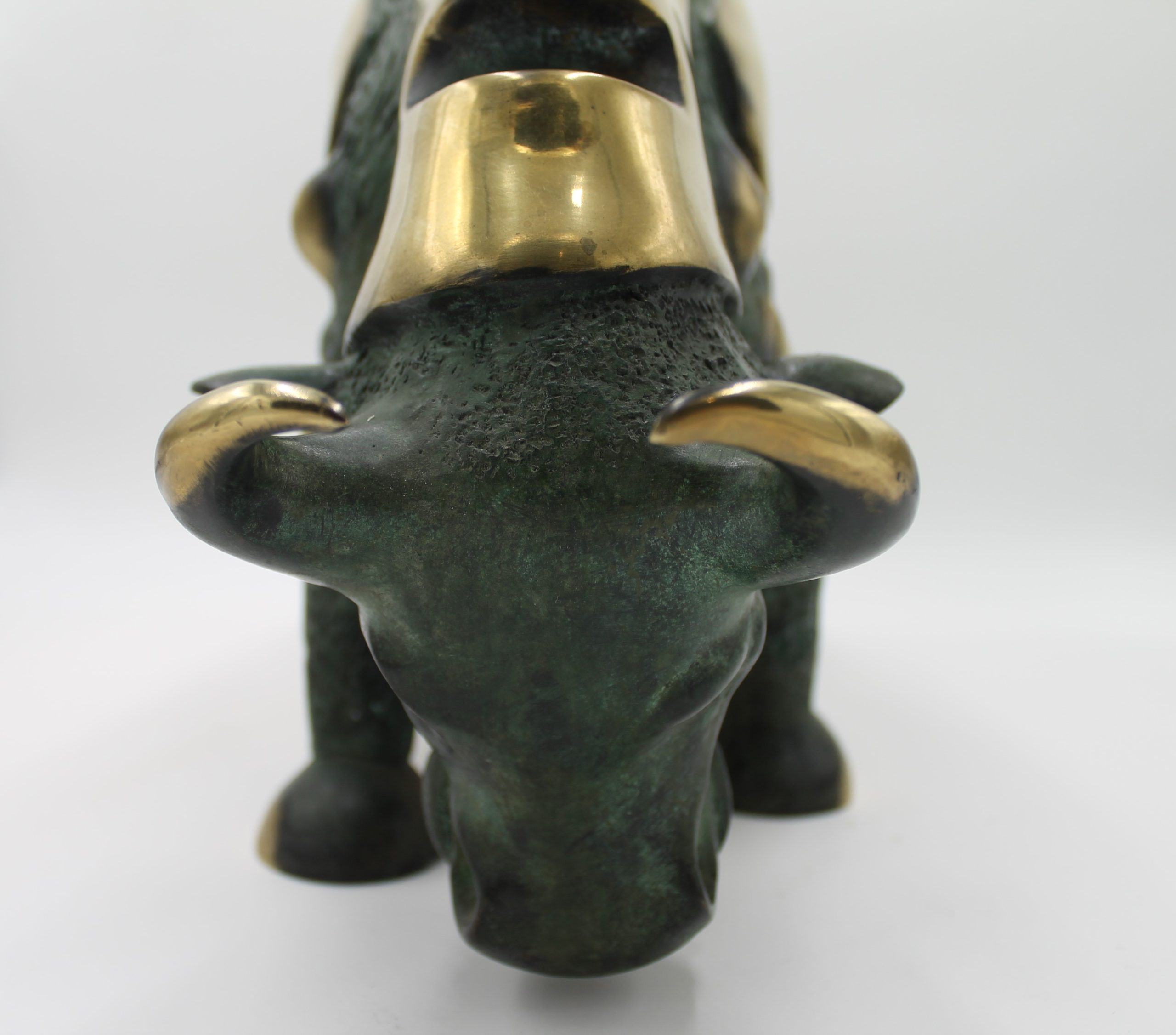 A abstract bronze sculpture of a bull with various patches of gold colouring over it.