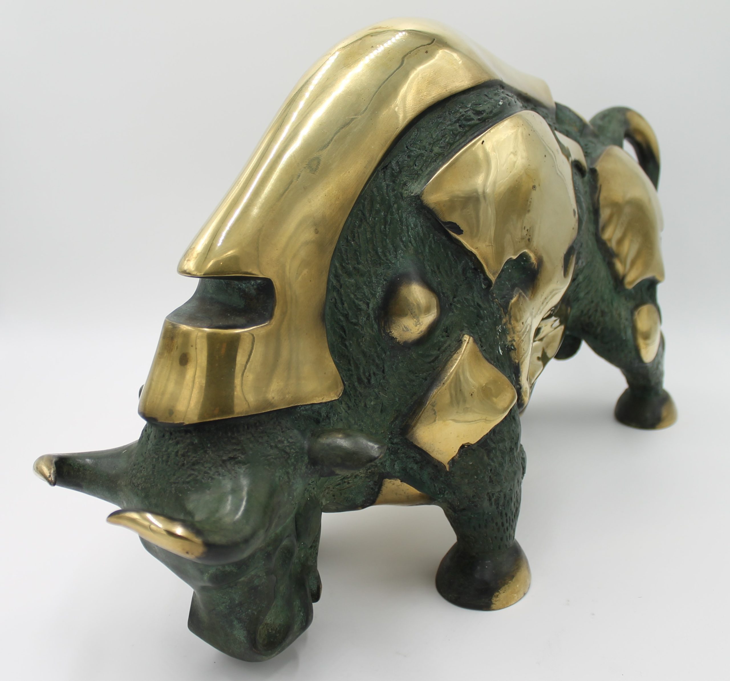 A abstract bronze sculpture of a bull with various patches of gold colouring over it.