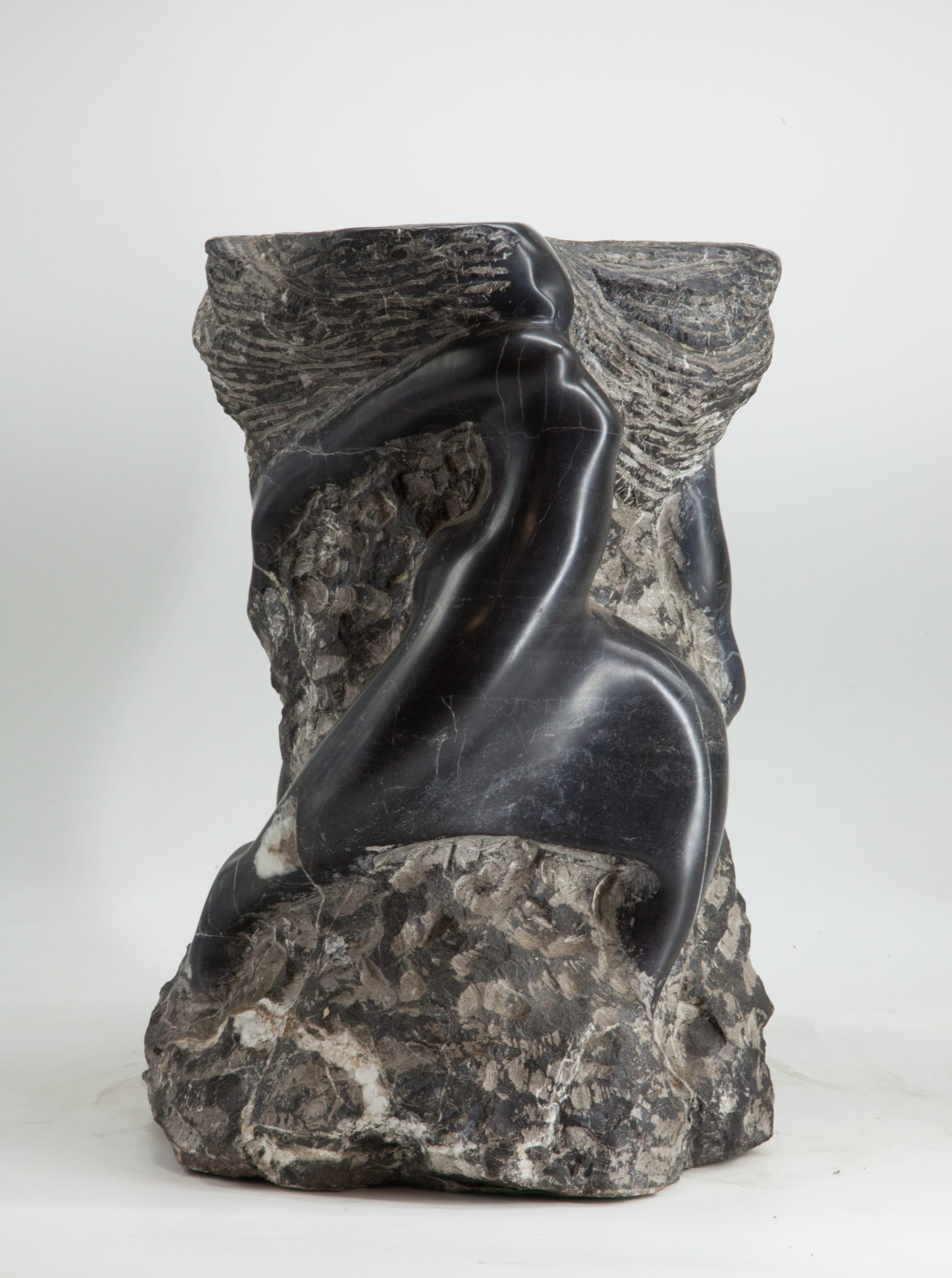 An abstract and modern sculpture depicting figures emerging from the marble.