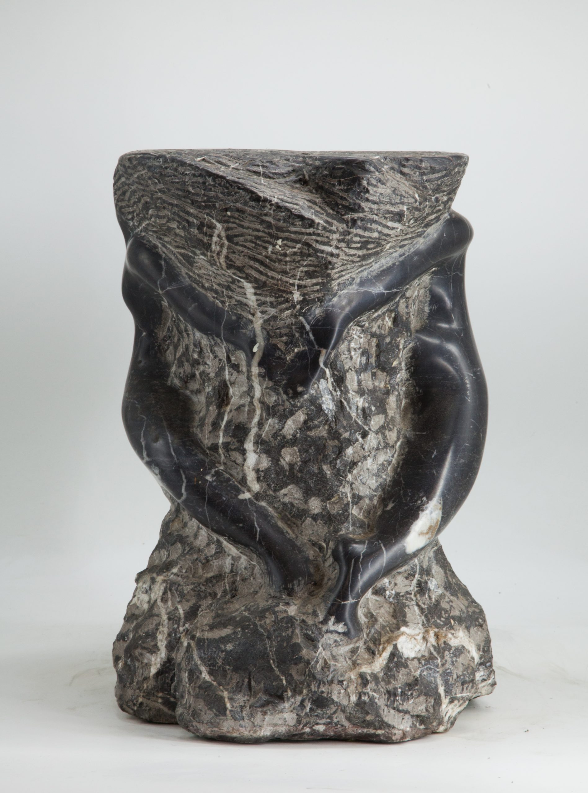 An abstract and modern sculpture depicting figures emerging from the marble.