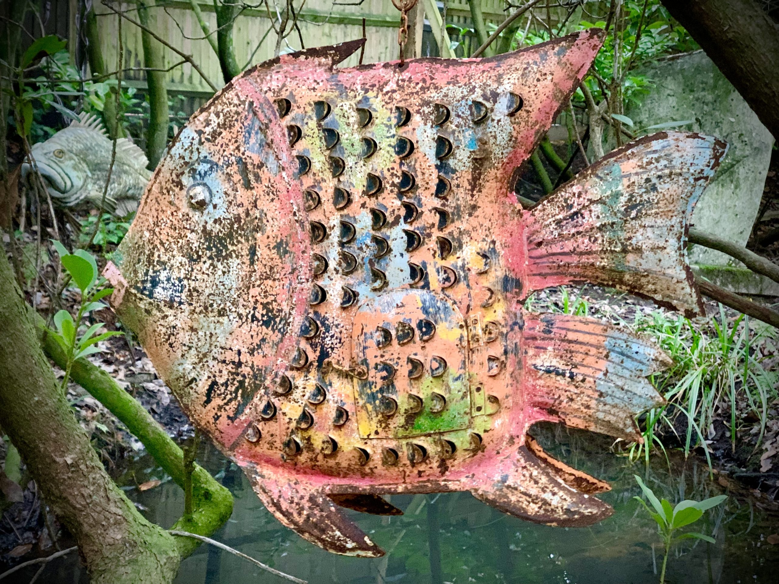 A painted tin fish sculpture which is also a candle holder.