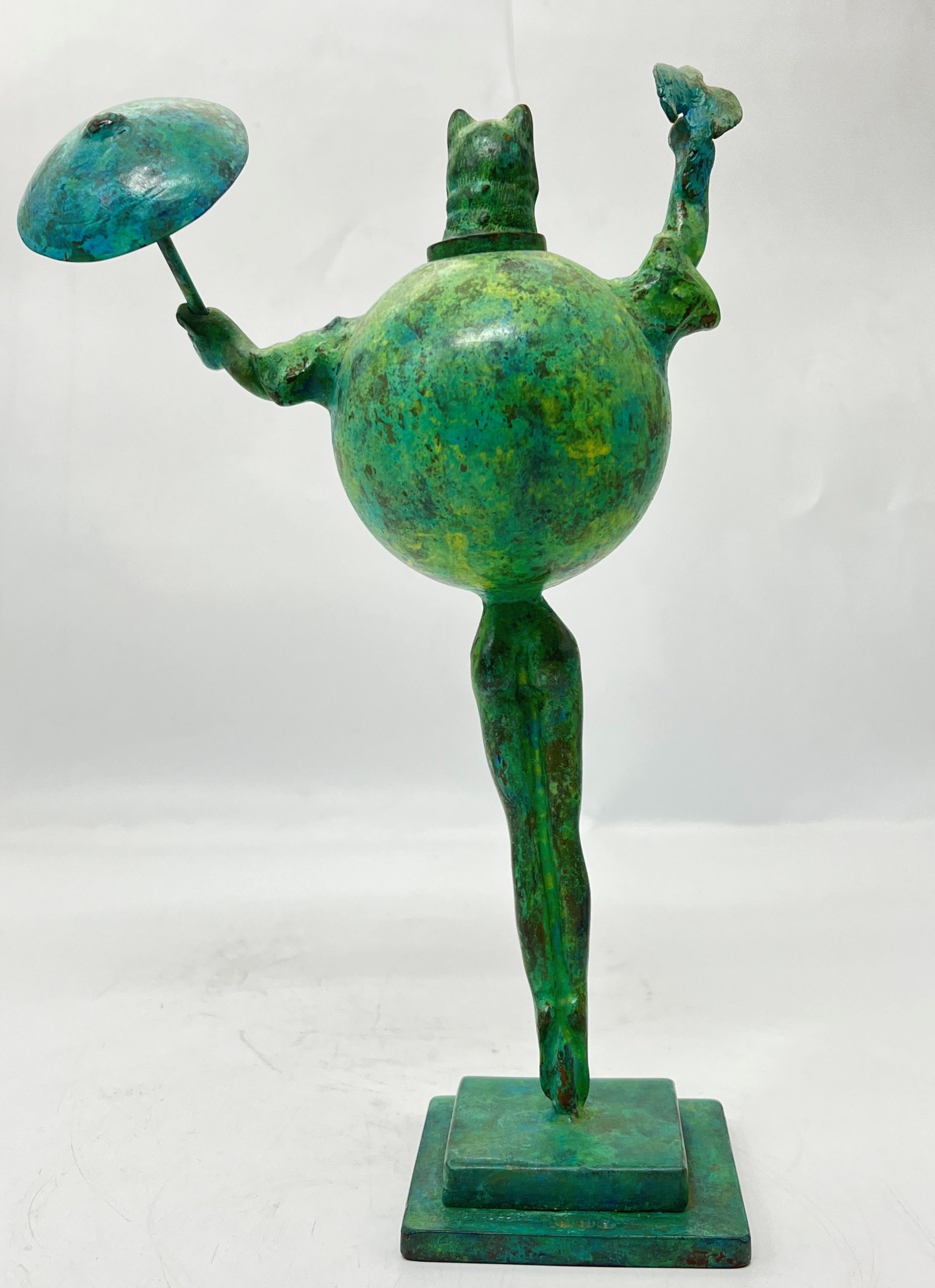 A modern and abstract smaller scale sculpture of a cat stood up straight whilst holding a bird in one hand and an umbrella in the other.