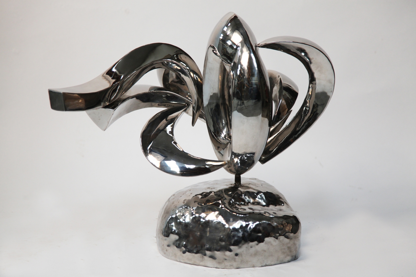 A abstract stainless steel sculpture of different curves and shapes, mounted onto a block.