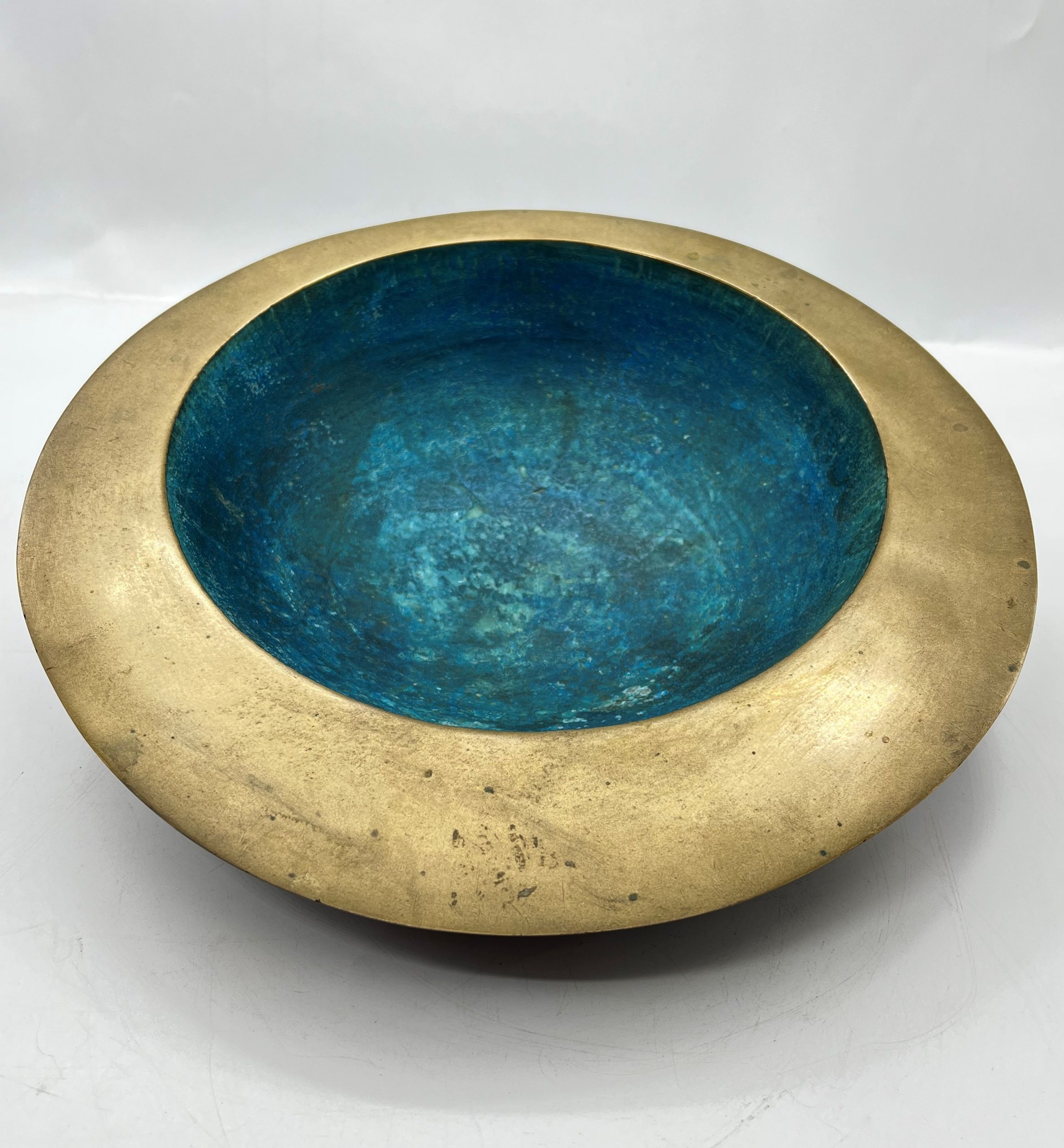 A abstract bronze sculpture of a bowl with a blue and gold finish.