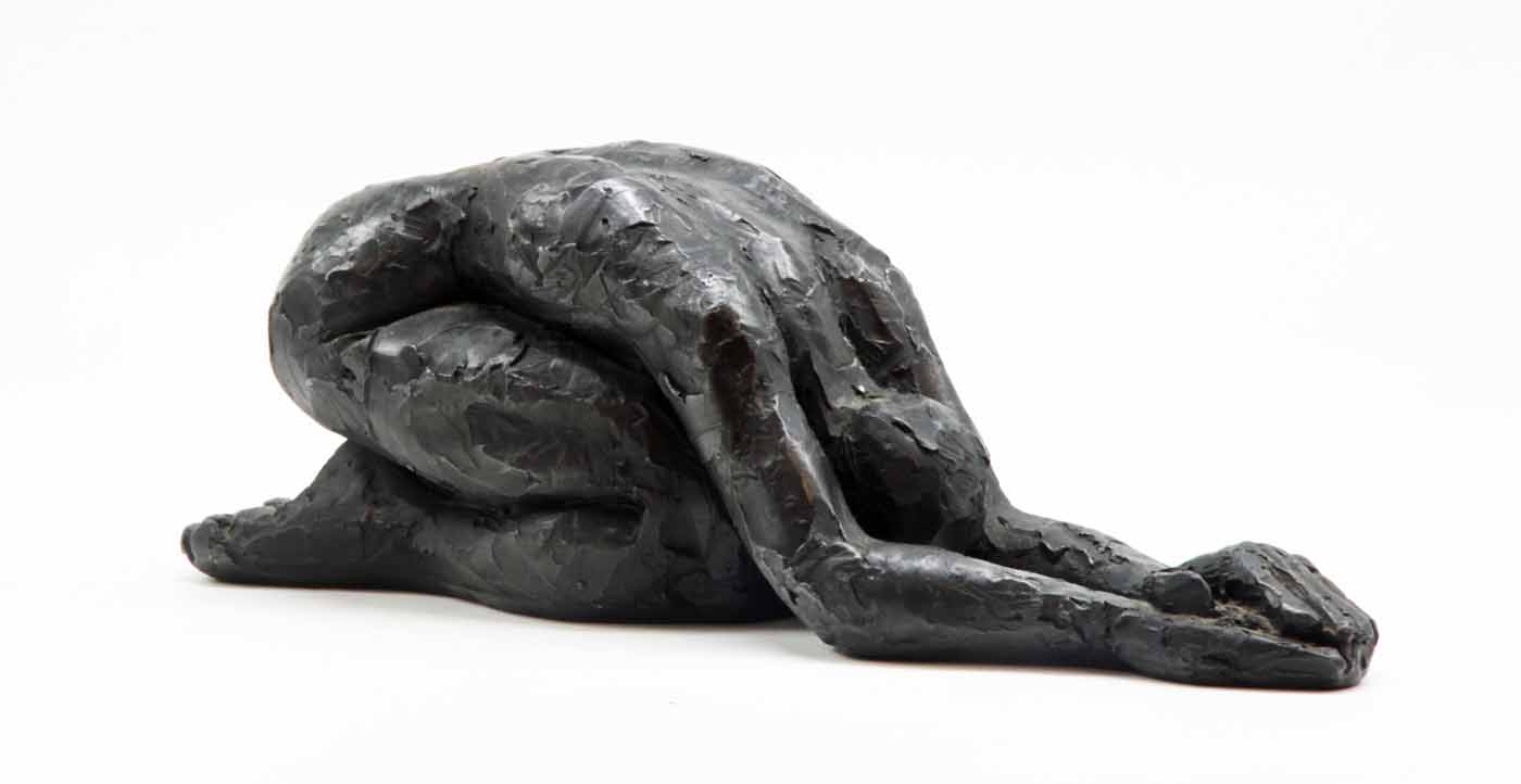 A figurative bronze sculpture of a woman folding forwards with her arms in front.