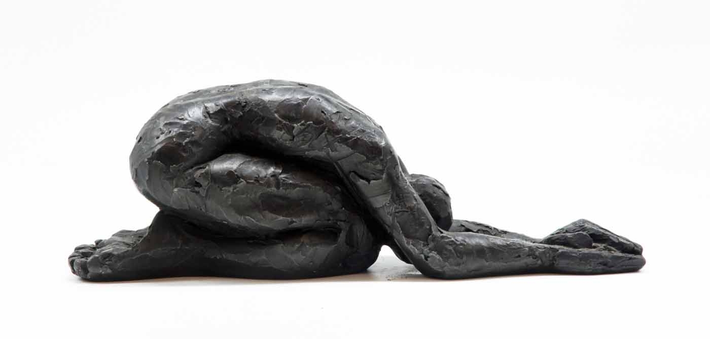 A figurative bronze sculpture of a woman folding forwards with her arms in front.